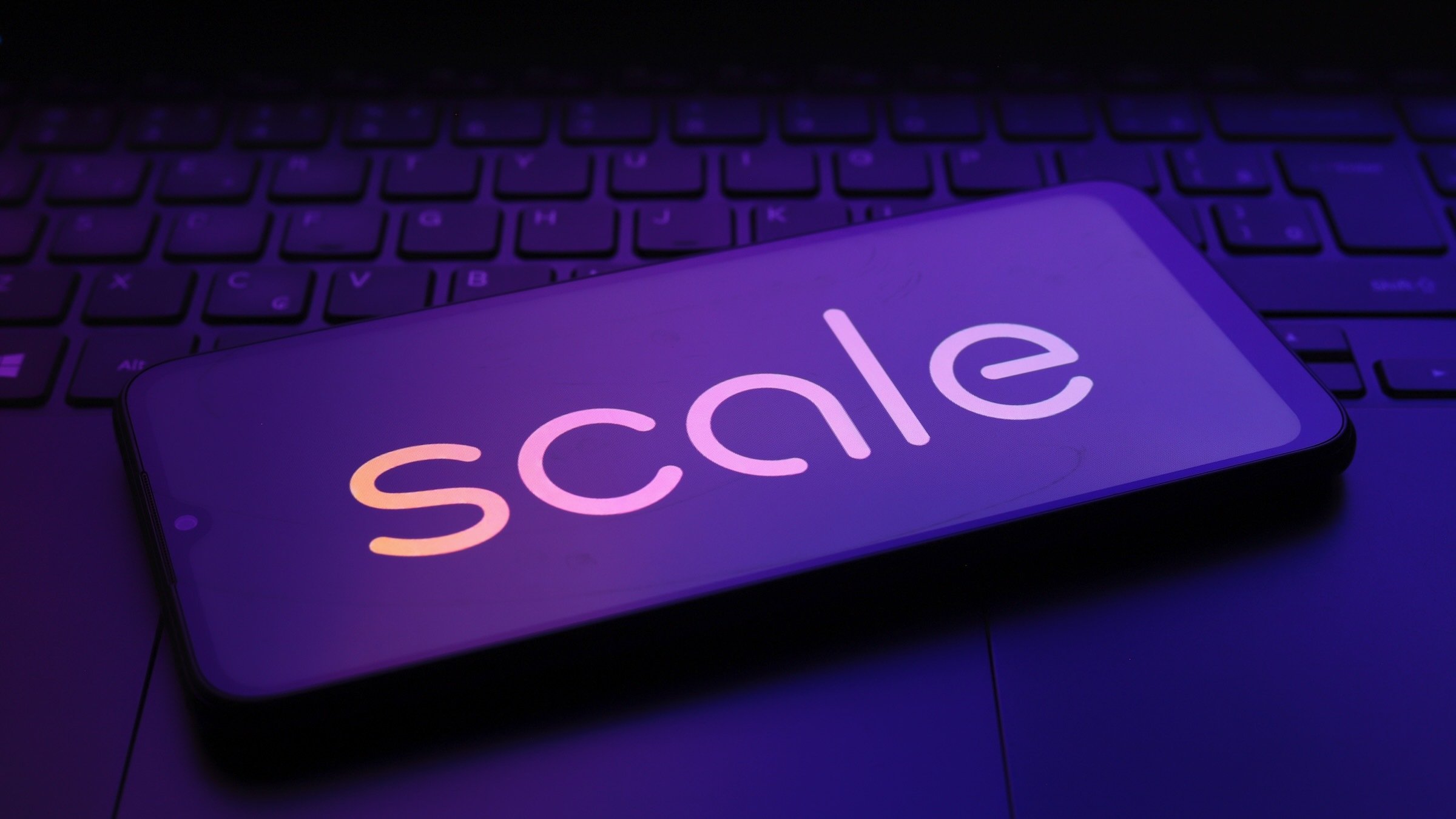 a smartphone with the scale logo lays atop a laptop keyboard