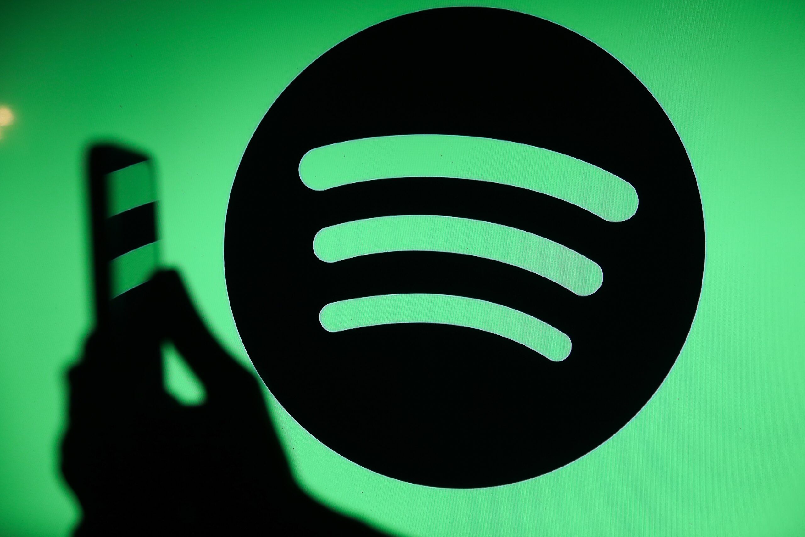 The Spotify logo displays on a screen with a person holding a phone in Knurow, Poland, on September 20, 2025.