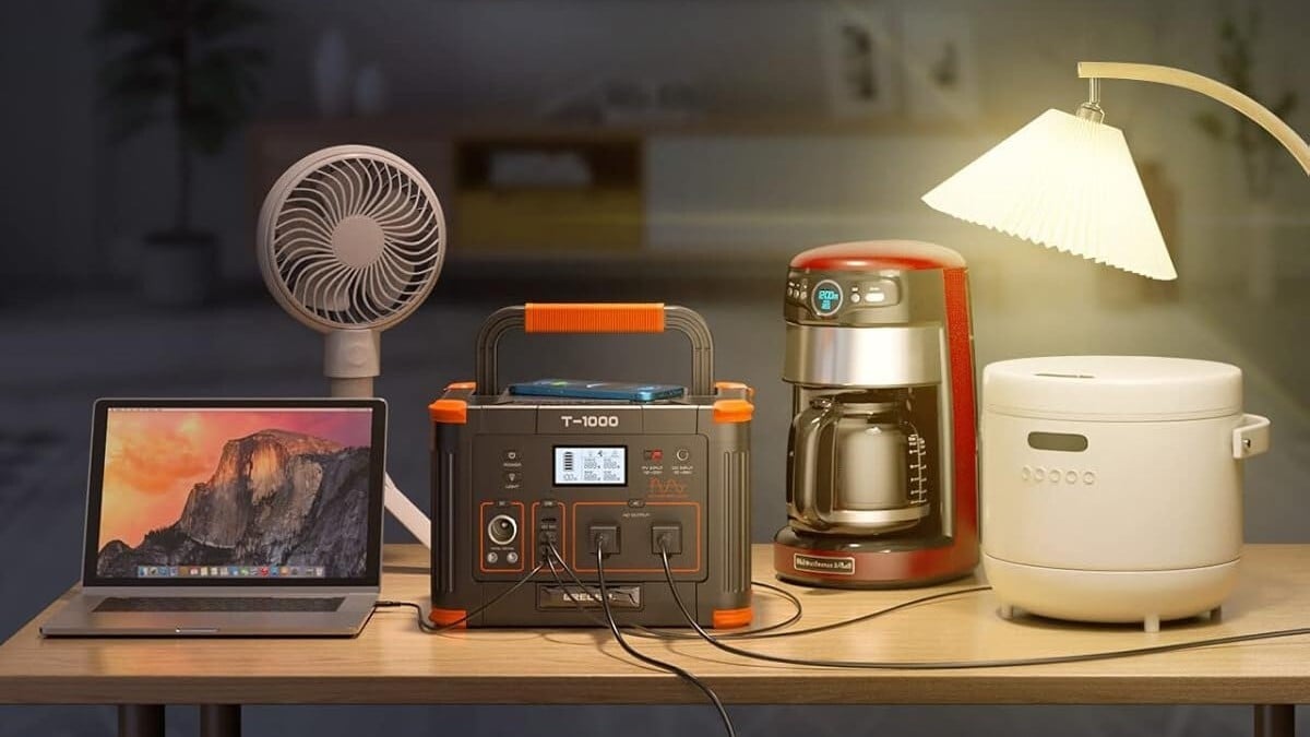 the grecell t-1000 portable power station sits on a table powering a lamp, coffee maker, rice cooker, and more.