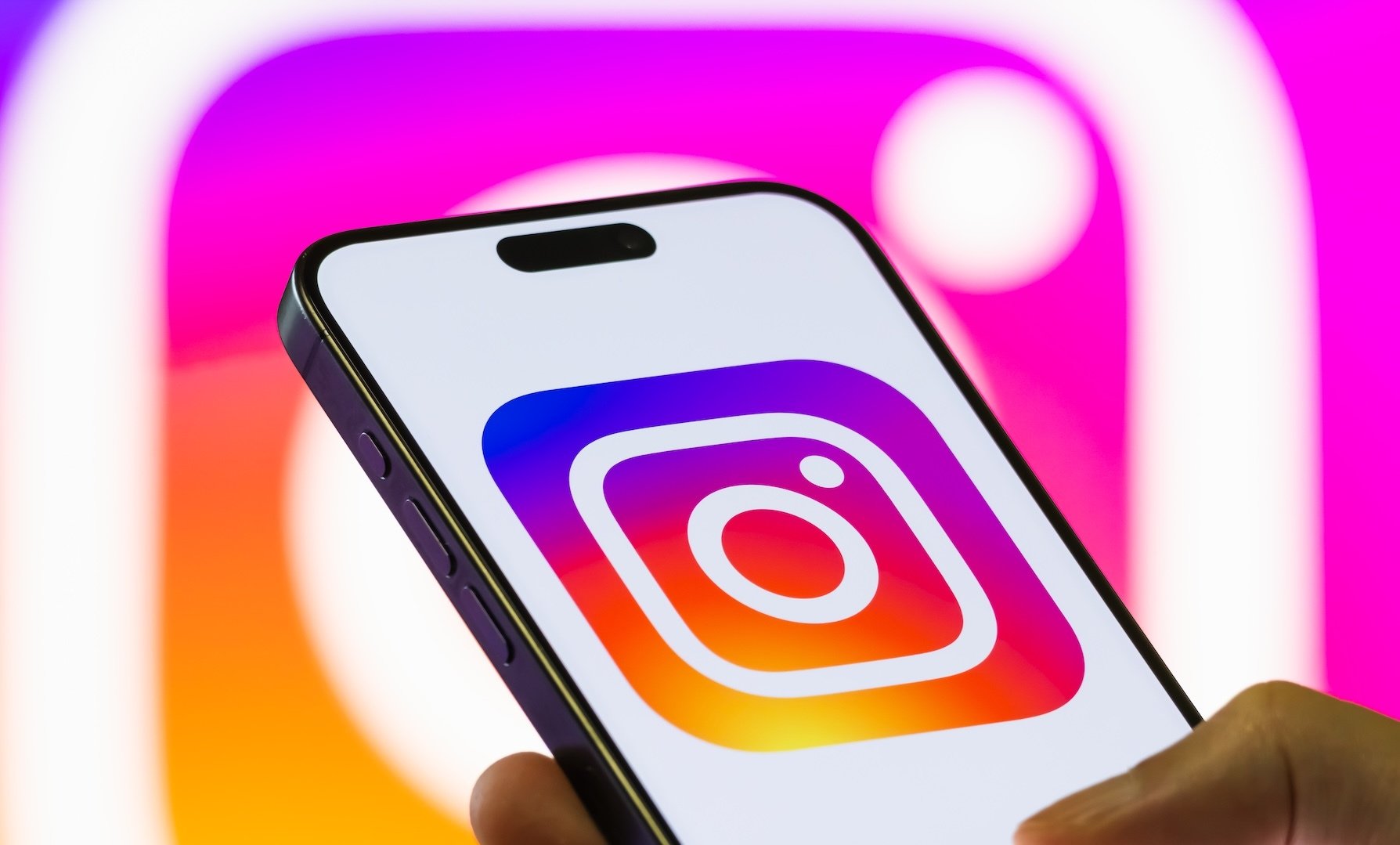 An Instagram logo on a phone in front of another Instagram logo.