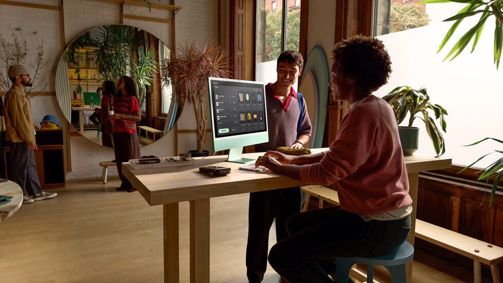 woman using Apple M4 iMac at desk with other people surrounding