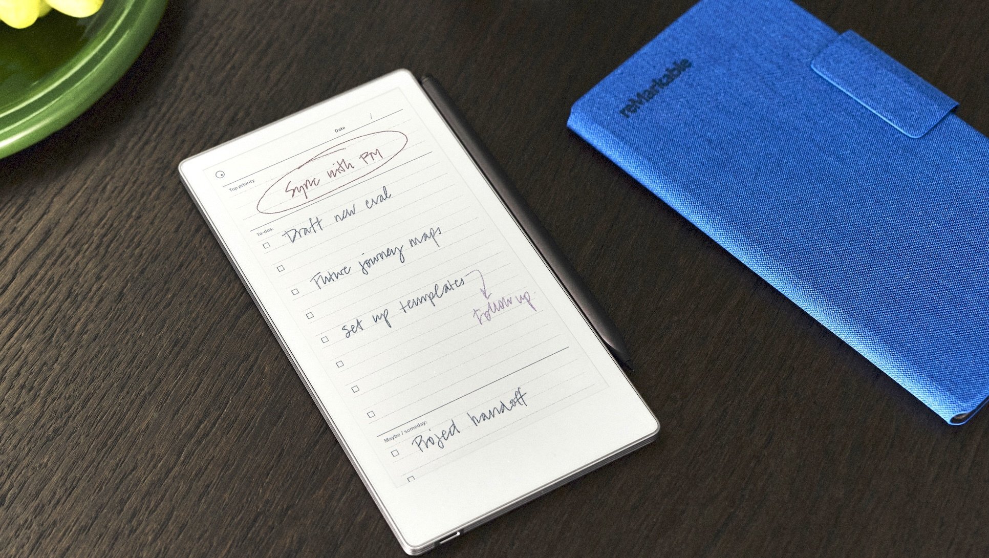 A thin, small tablet with an e=ink screen and its blue case on a table. 