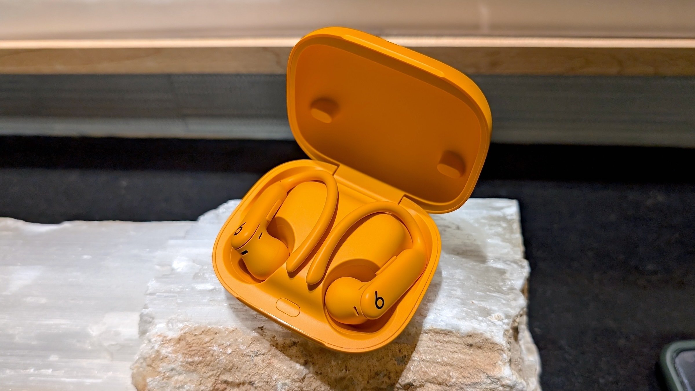 beats powerbeats pro 2 earbuds and charging case on stone plinth