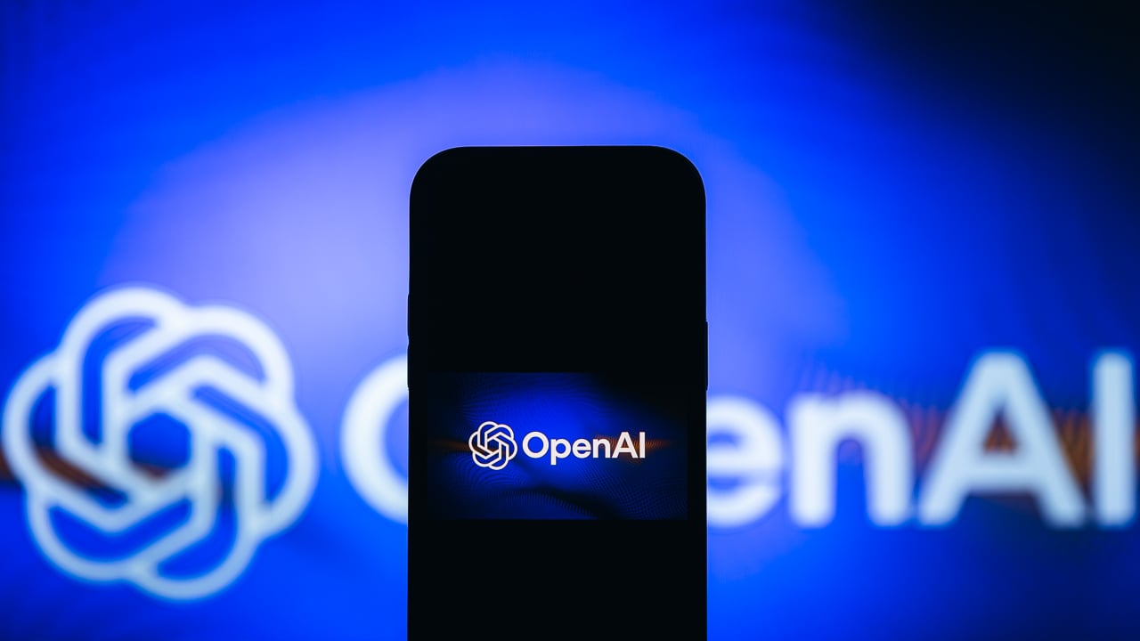 photo illustration of the OpenAI logo on a smartphone with the same logo in the background