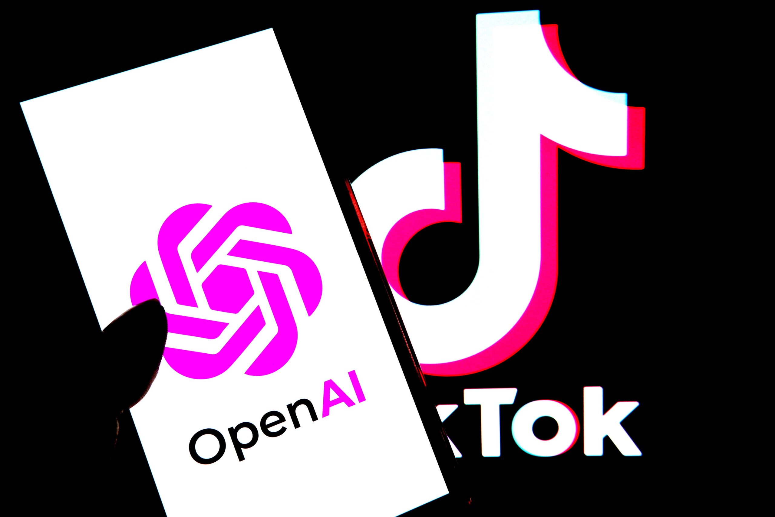 An Open AI logo is seen displayed on a smartphone with a Tiktok logo in the background.