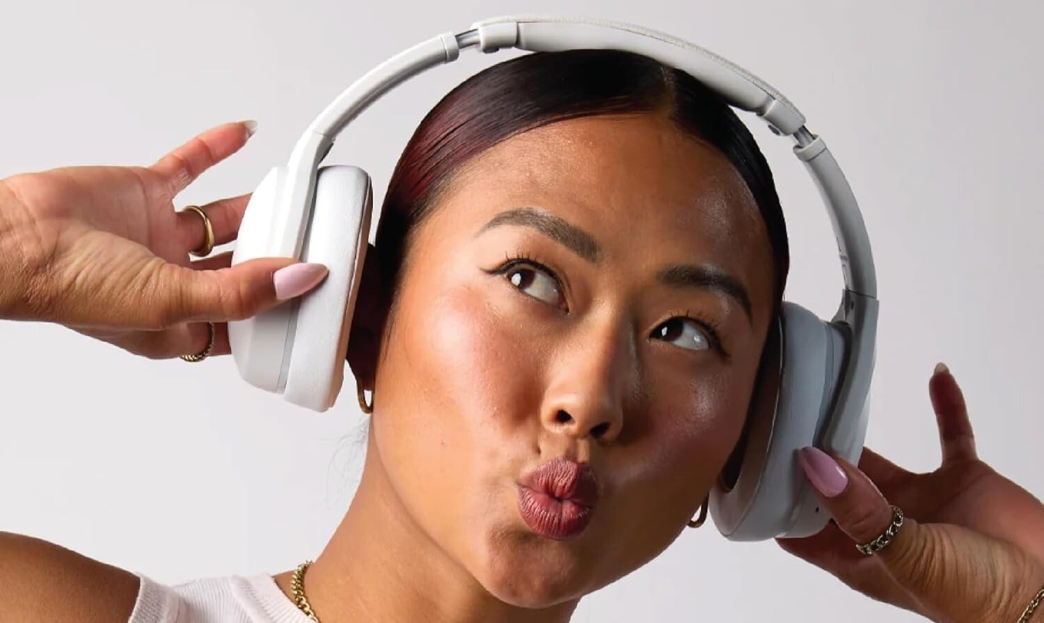 a person wears white skullcandy crusher evo headphones while wearing a white tank top
