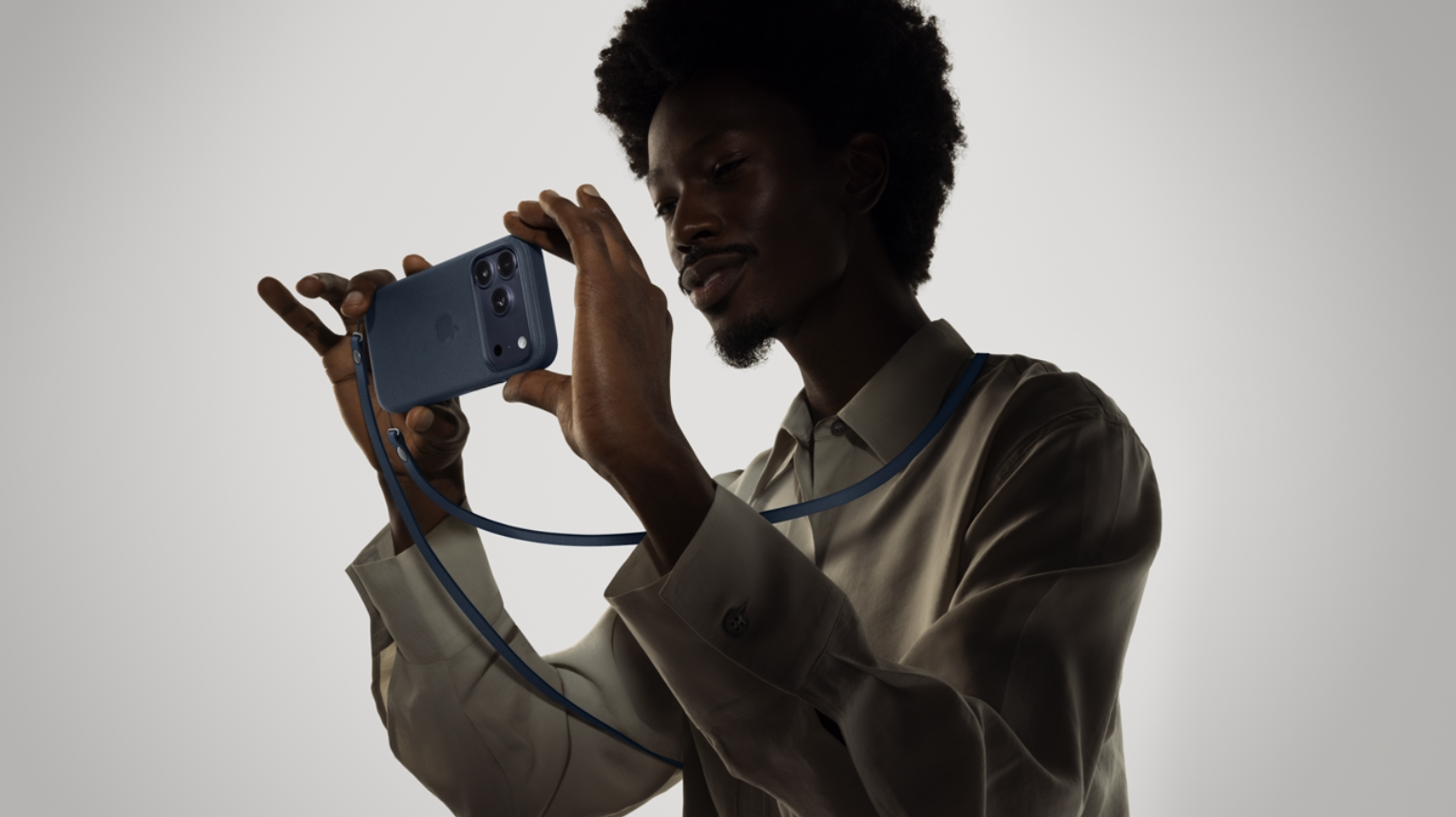 man holding an iphone with a crossbody strap