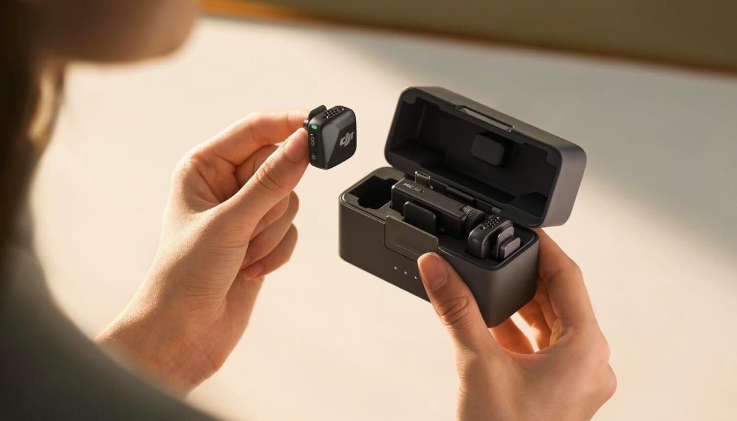 a person holds the DJI mic mini in her left hand, removing it from the case.