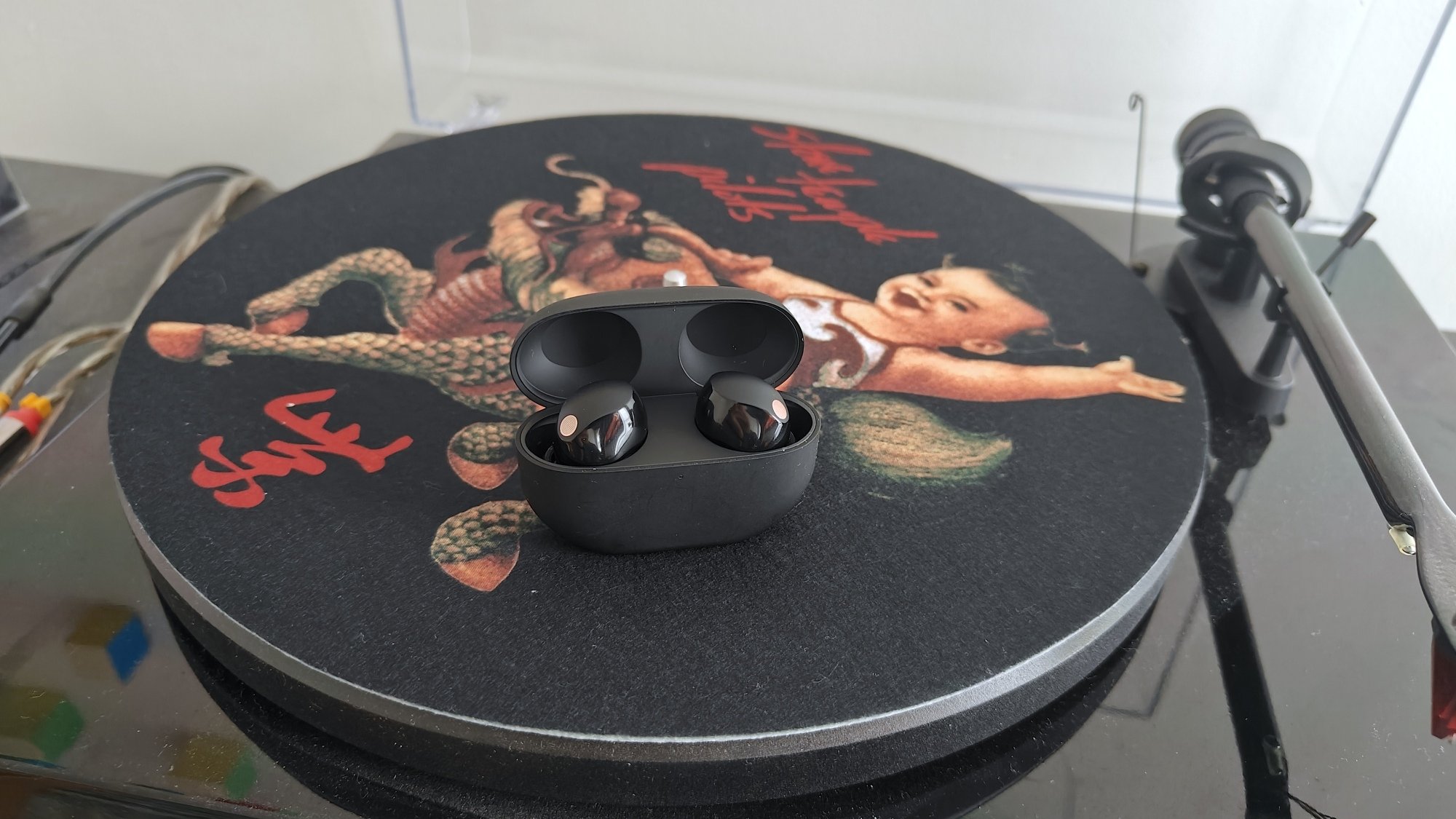 sony earbuds sitting on top of a record player turntable