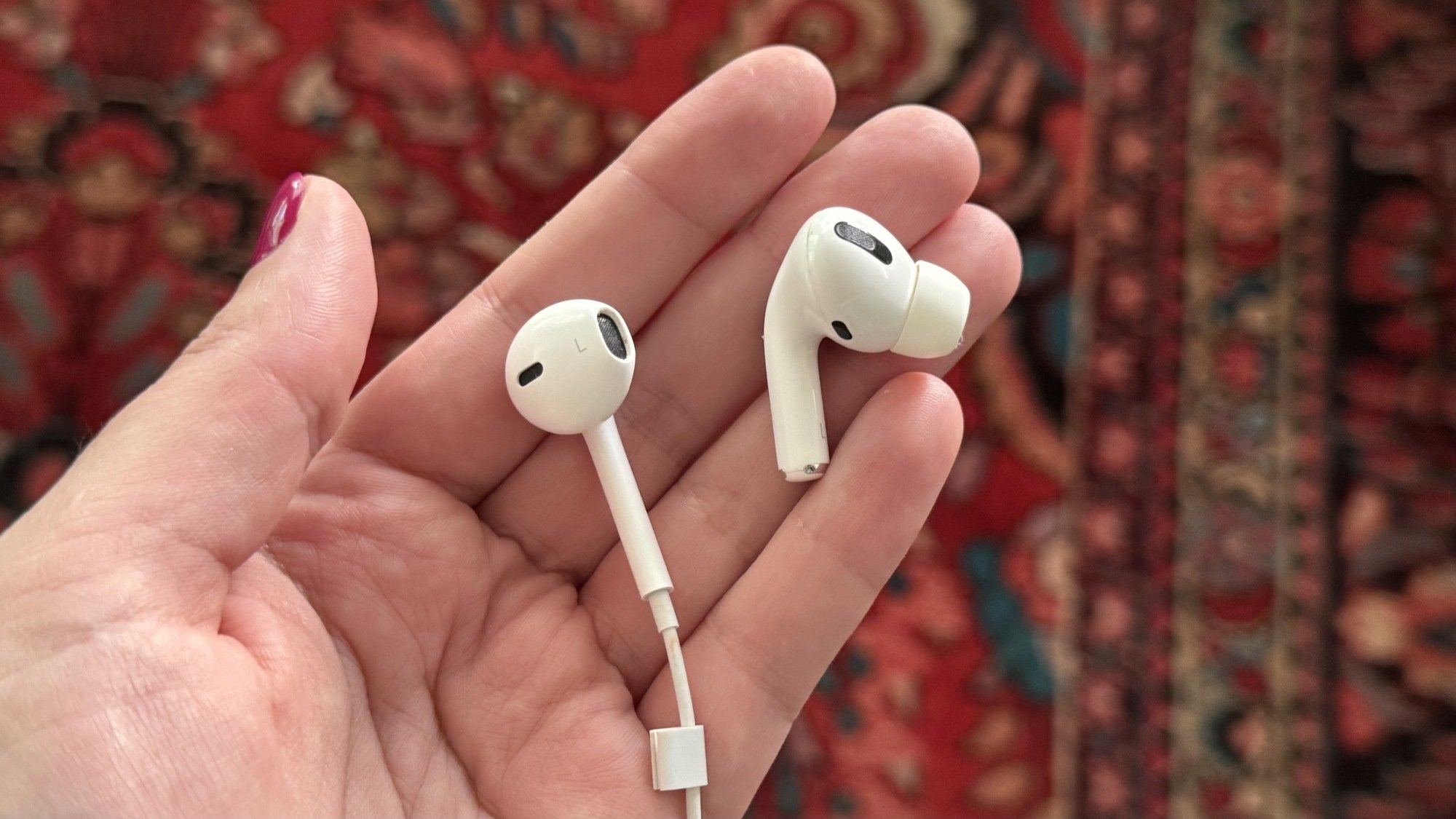a close-up of an earpod and an airpods pro earbud in a woman's hand
