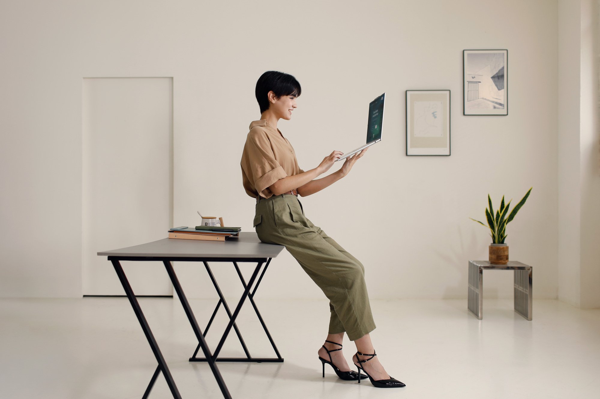 a woman holding the acer swift air 16 in a beige room