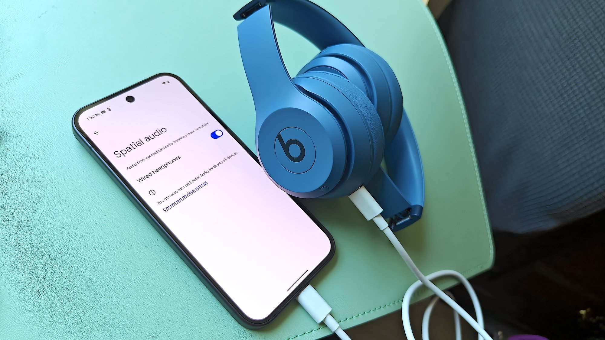 beats headphones and phone open to settings page with spatial audio toggled on