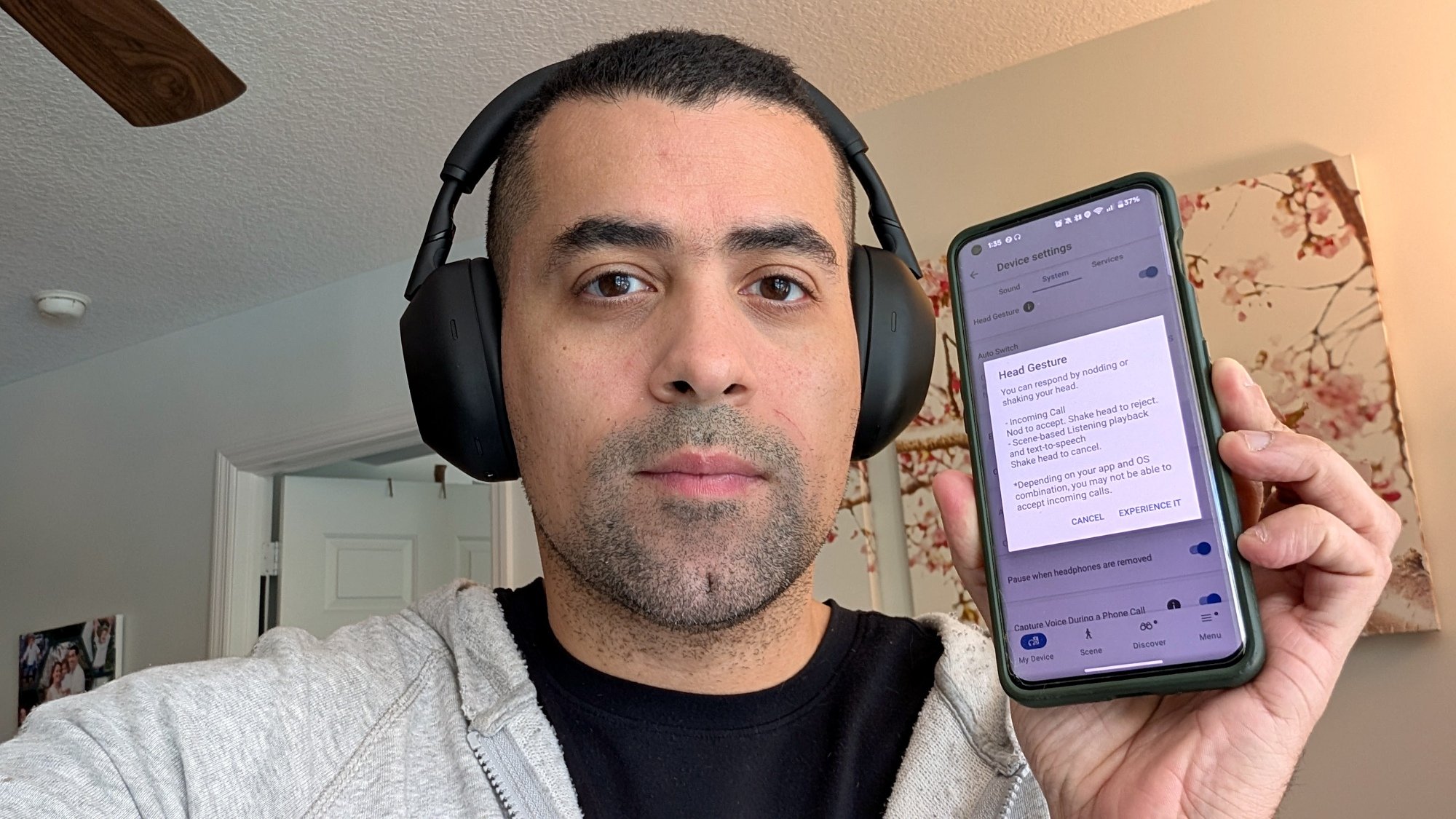 author wearing headphones and holding up phone with head gesture settings on screen