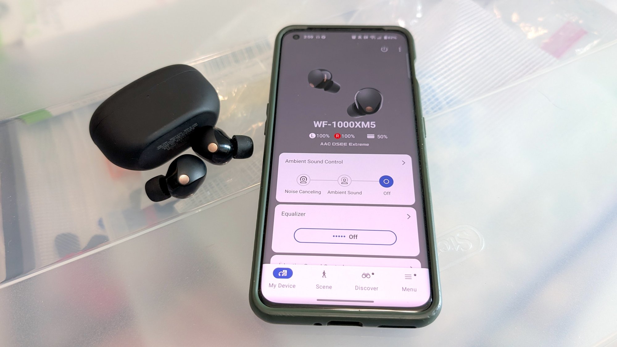 The Sony WF-1000xM5 sitting on a table next to a phone with Sony's app open and the devices paired