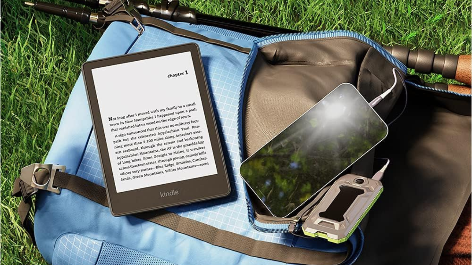 open bag laying on grass with Kindle Paperwhite, cell phone, and charger