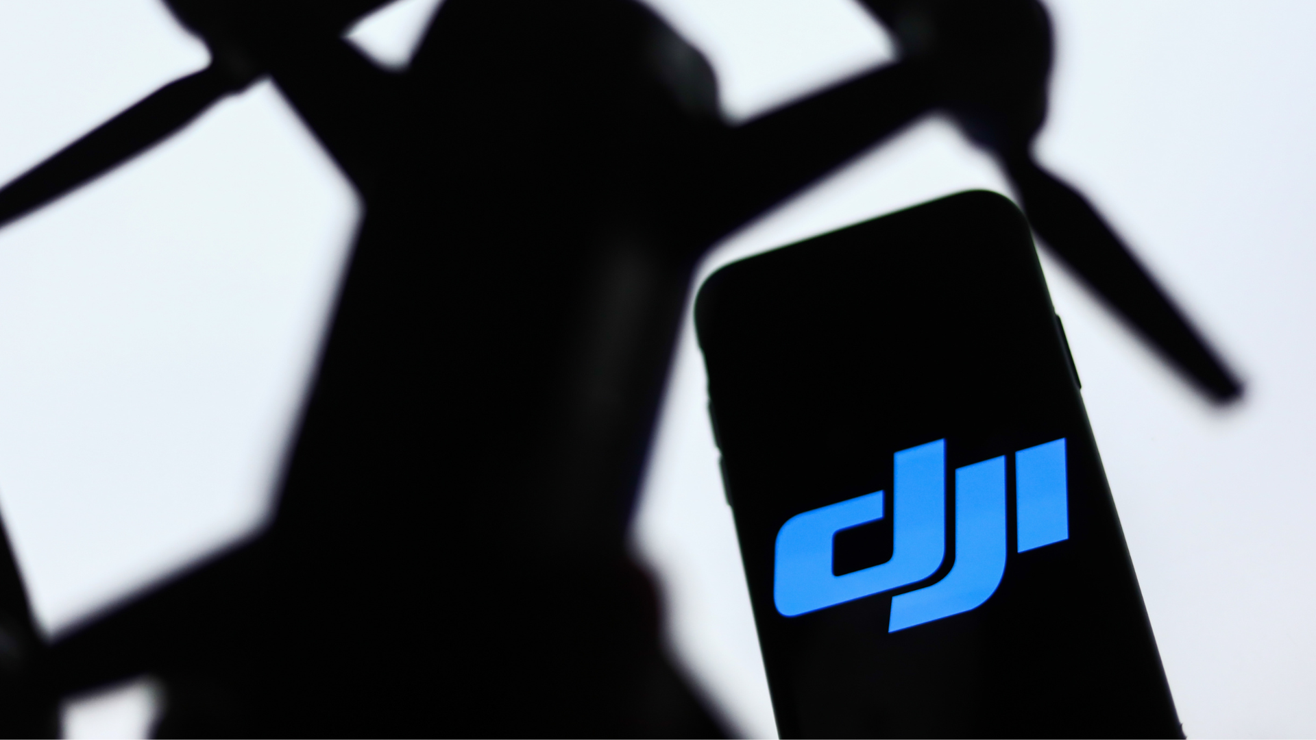 DJI logo displayed on a phone screen and a silhouette of a drone.
