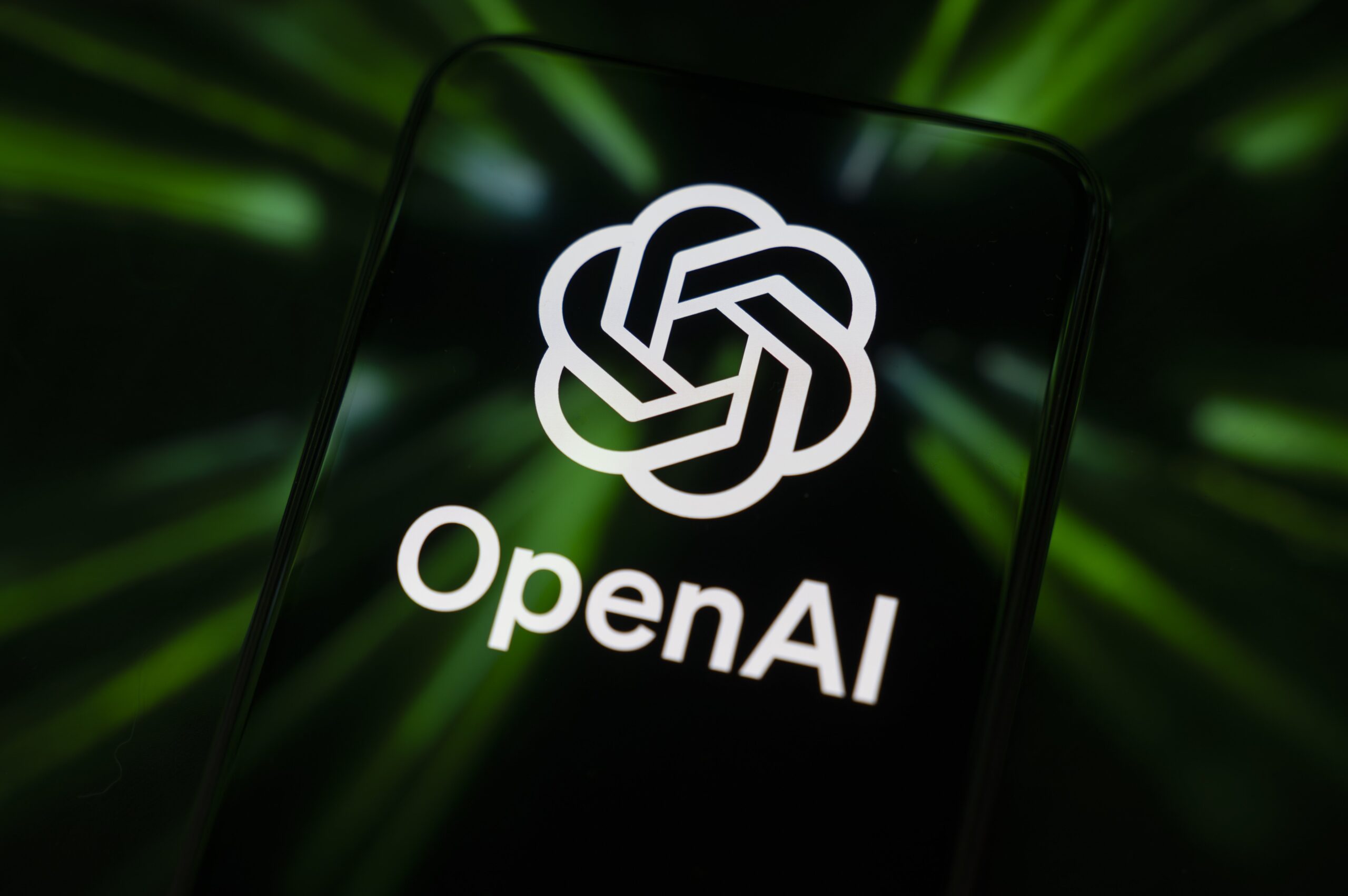 The OpenAI logo displays on a smartphone screen reflecting green beams
