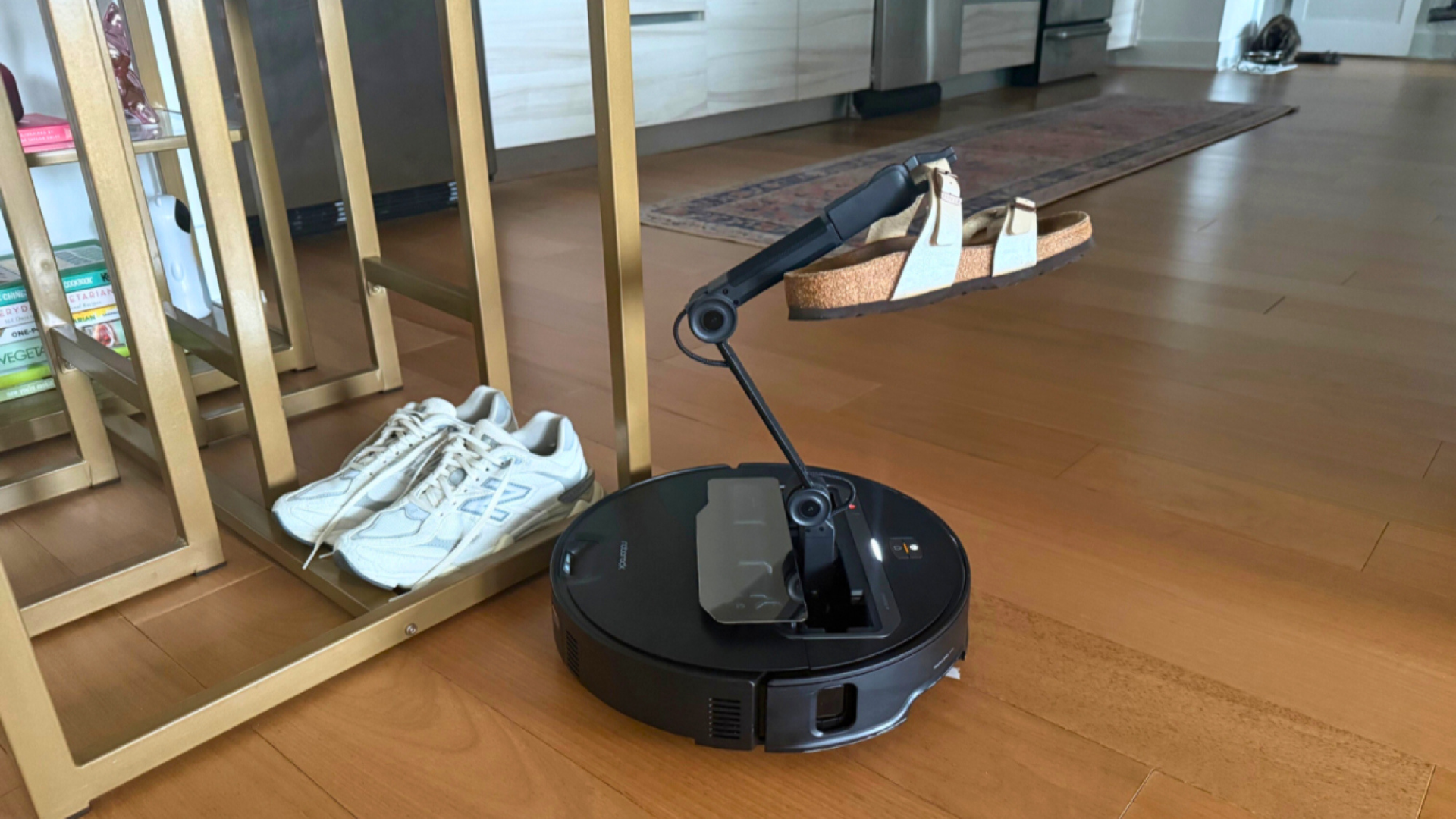 A robot vacuum with mechanical arm lifting up a sandal.