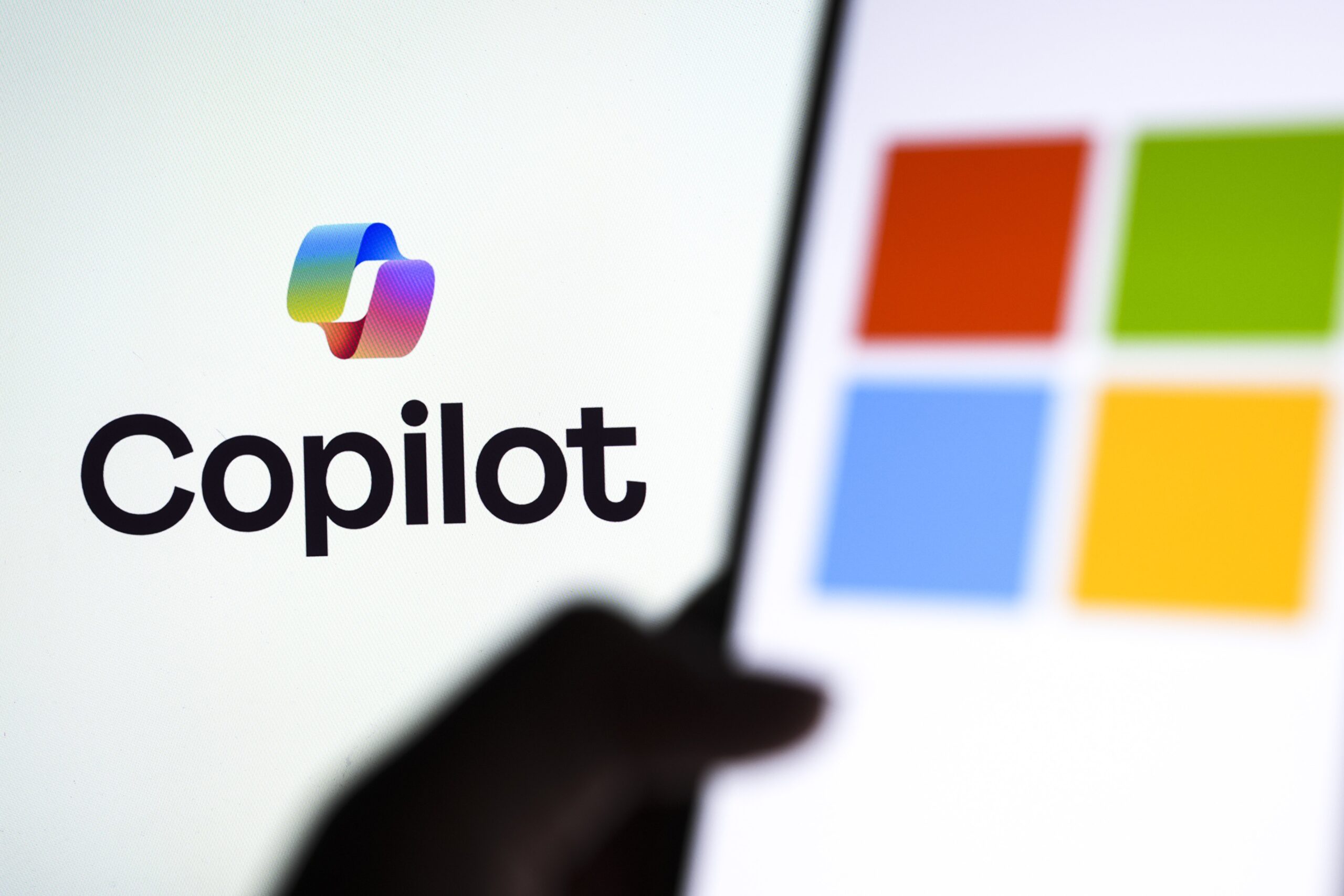 The Microsoft logo is displayed on a mobile phone screen in front of the Copilot logo in Ankara, Turkiye on October 28, 2025. 