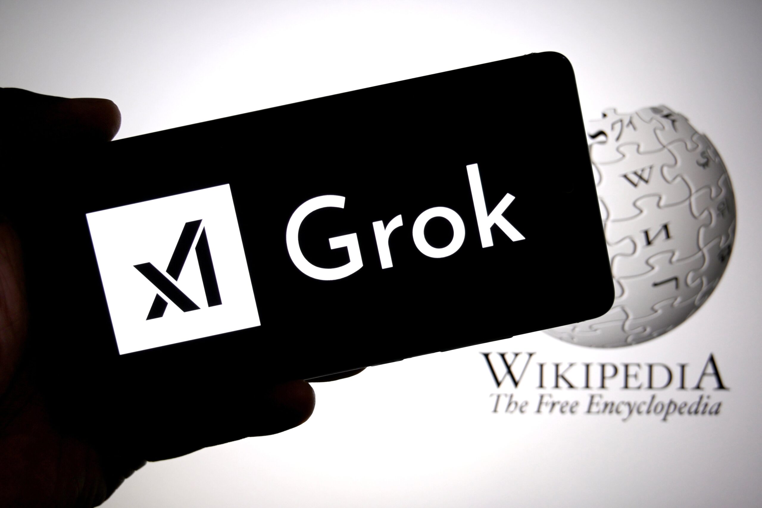 Grok logo on mobile device over Wikipedia website