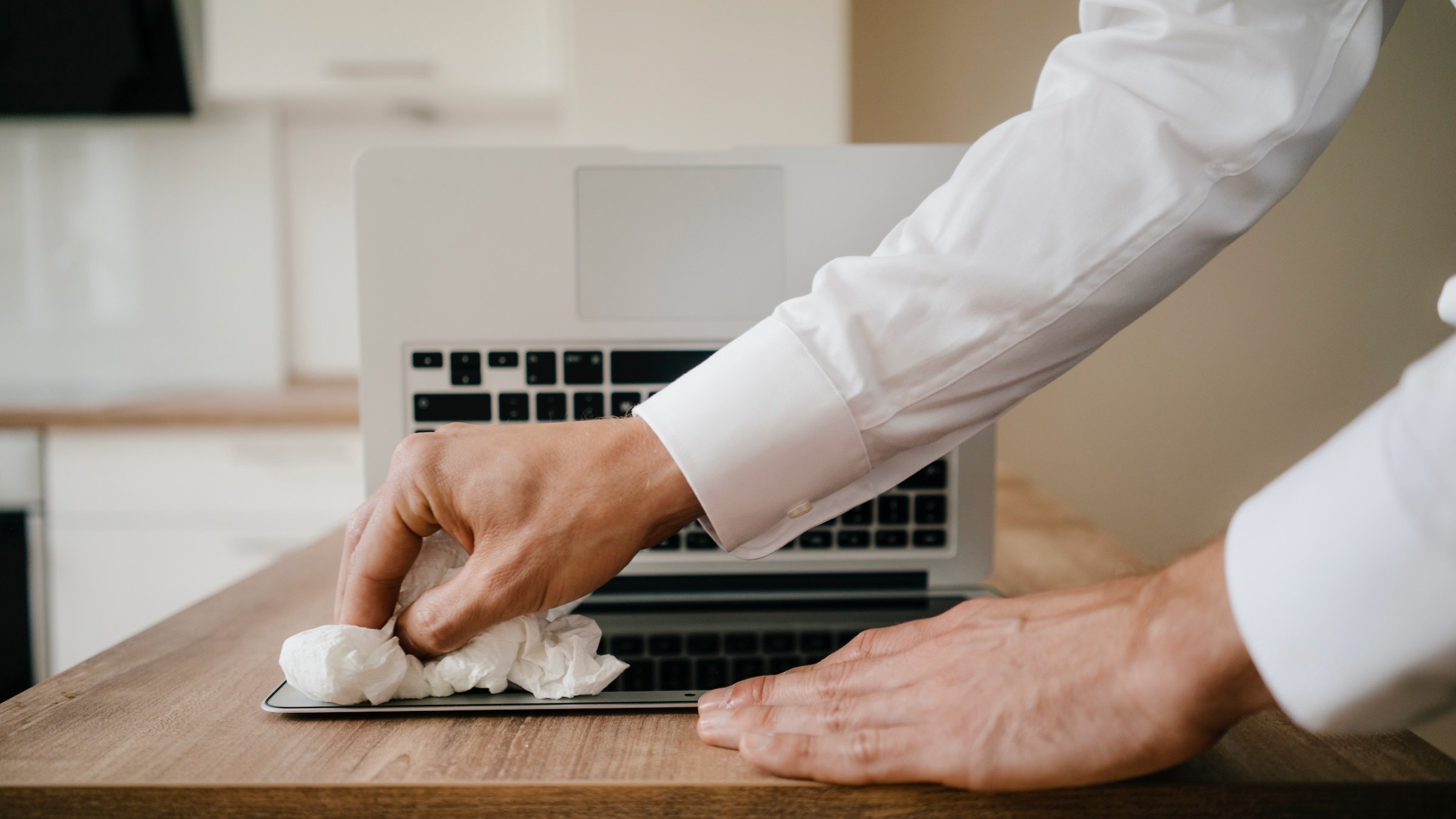 businessman cleaning laptop screen while laptop is upside down