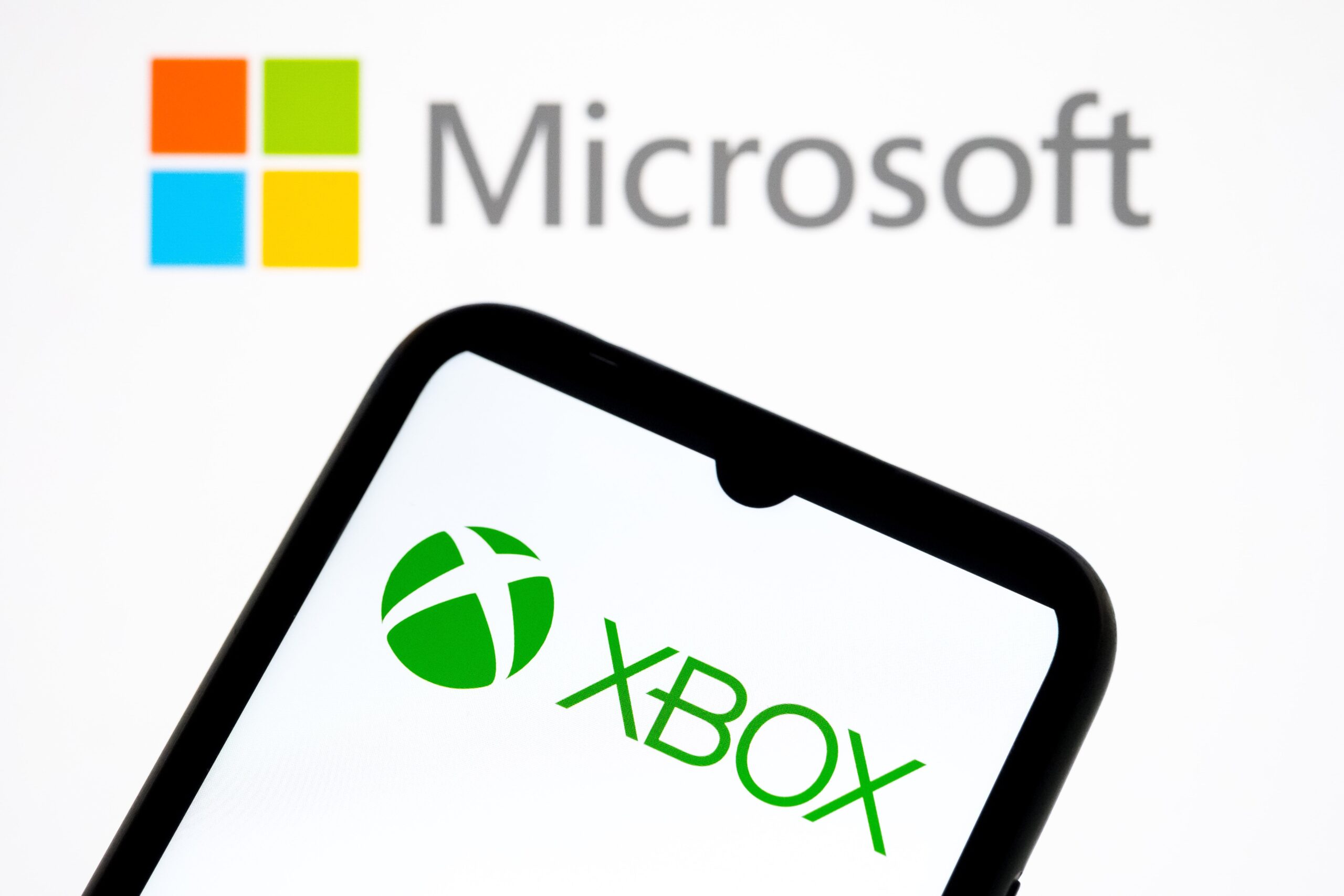 xbox logo on a phone in front of a microsoft logo