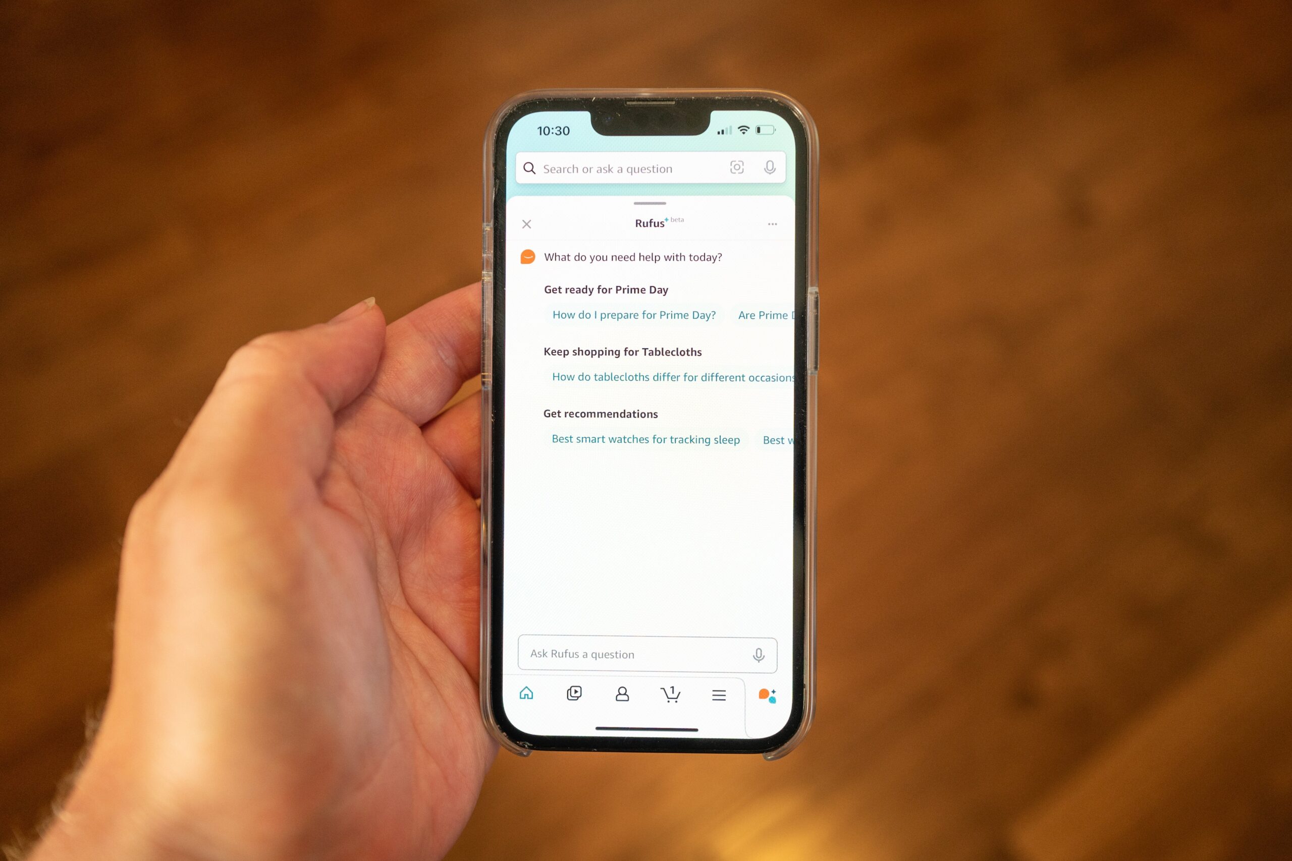 Person's hand holding an iPhone and using the Amazon Rufus AI system
