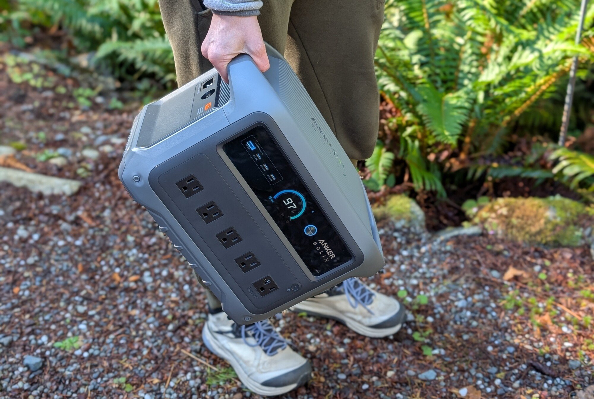 a person holds the anker solix c1000 gen 2in one hand while standing outside