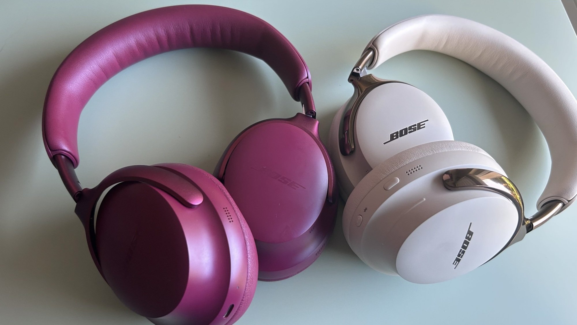 plum bose qc ultra headphones next to sandstone bose qc ultra 2 headphones on desktop