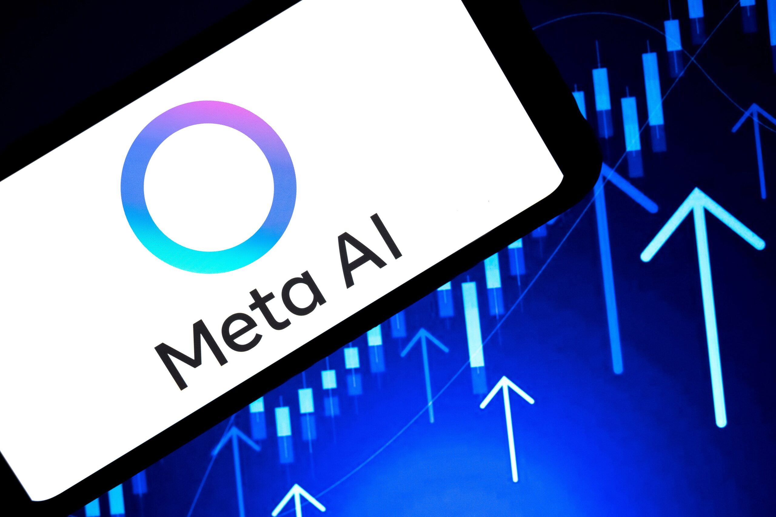 The Meta AI logo appears on a smartphone screen, and a stock exchange curve chart displays as the background on a laptop computer screen, in this photo illustration in Athens, Greece, on October 30, 2025. Meta Platforms Inc. aims to sell at least $25 billion of investment-grade bonds on Thursday, according to people familiar with the matter, borrowing money as technology companies invest heavily in infrastructure for artificial intelligence.
