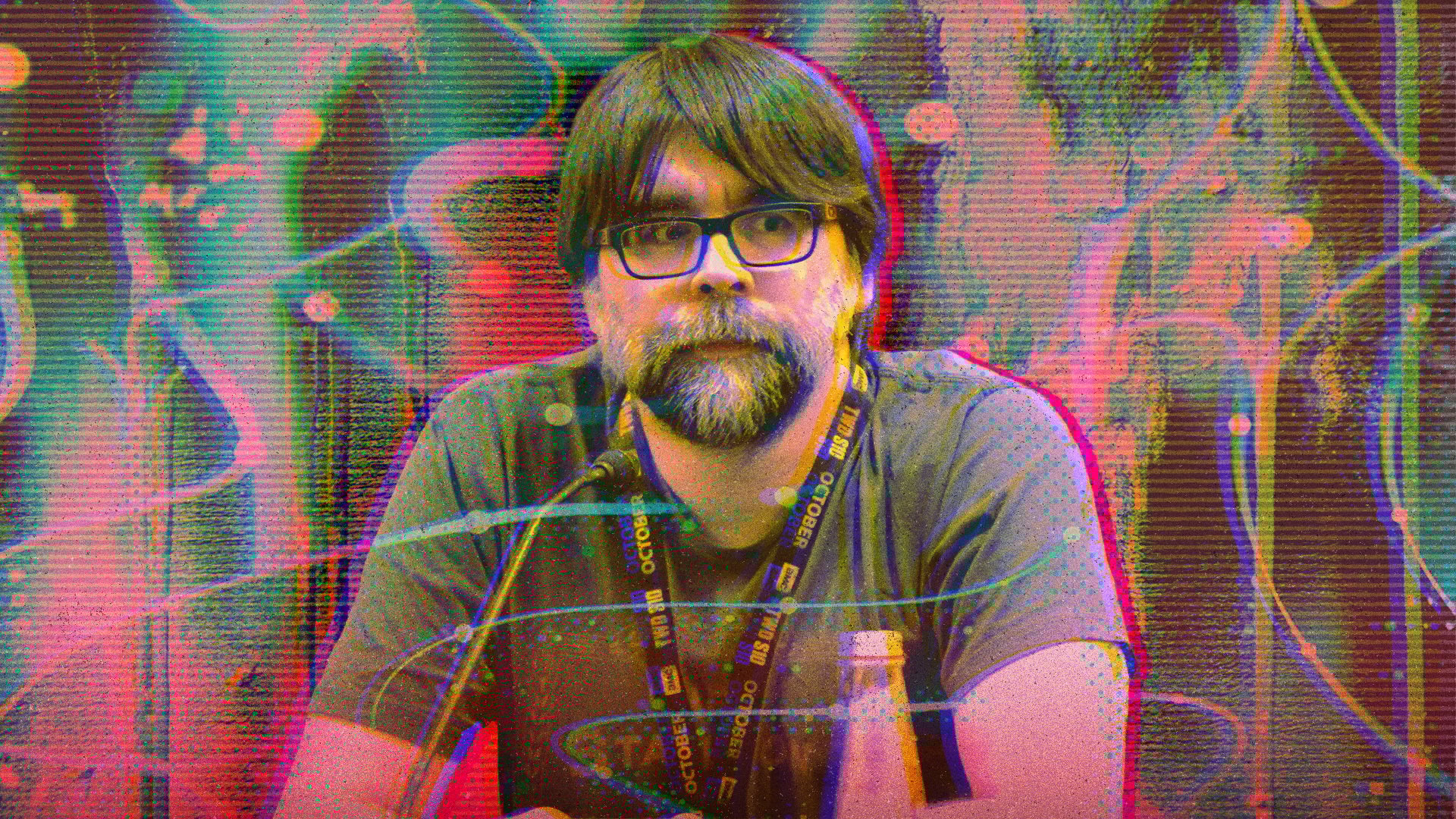 A man sits behind a podium with a microphone in front of him.