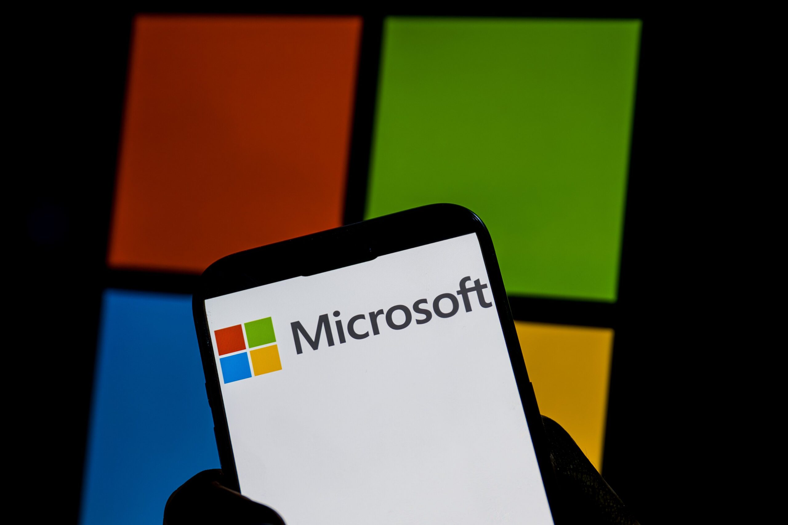 Windows logo in smartphone screen next to Microsoft logo against white background