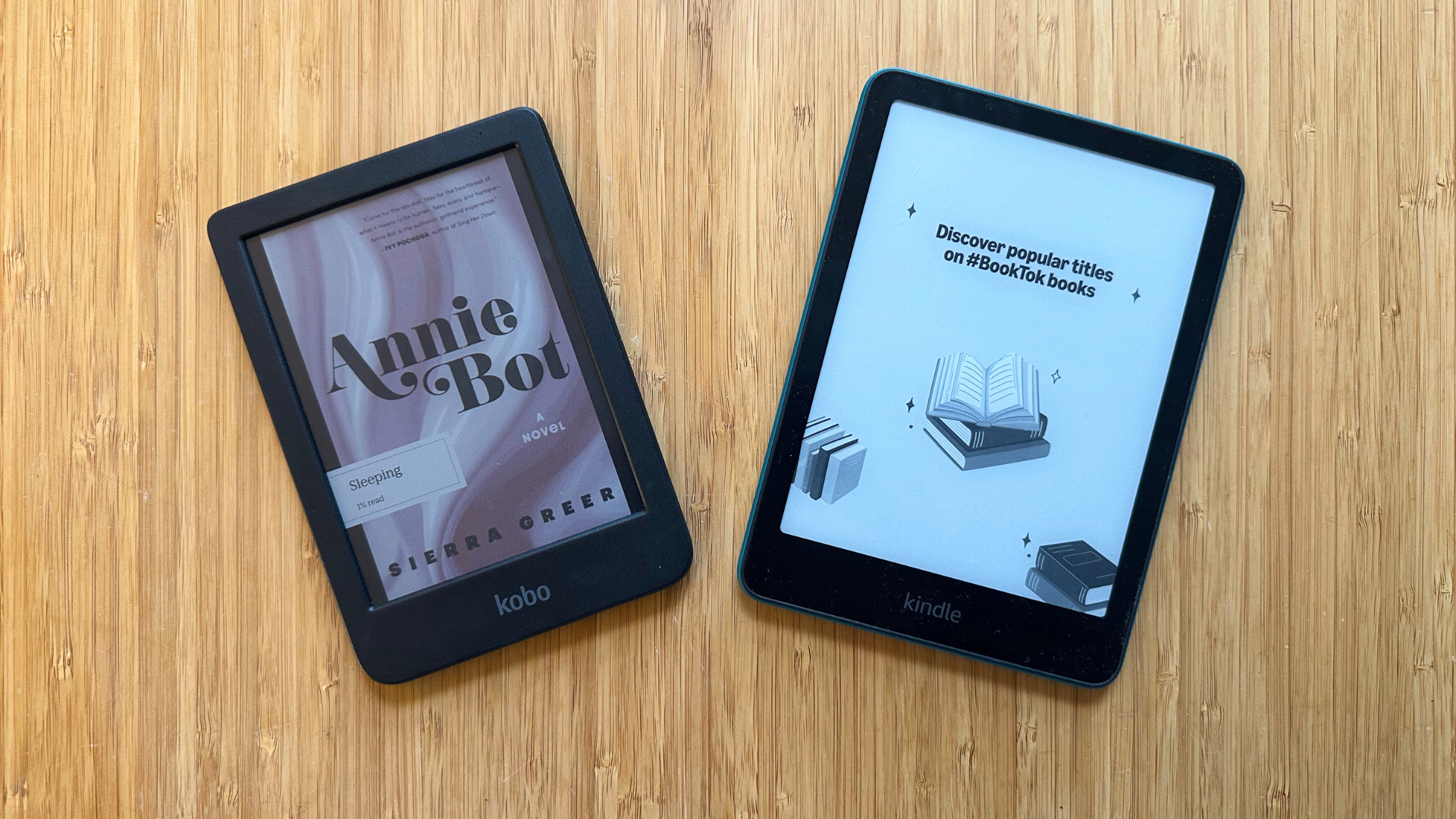 A Kobo Clara Colour and Kindle Paperwhite on a wood table