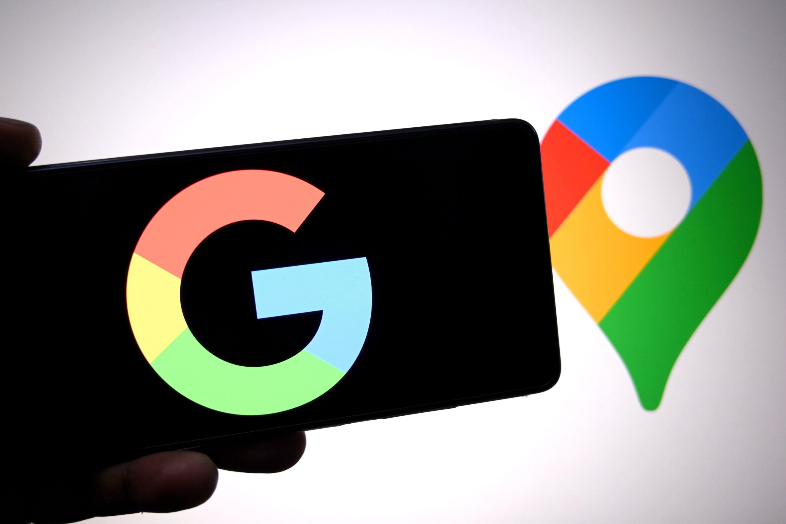 a Google logo is seen displayed on a smartphone with a Google Maps logo