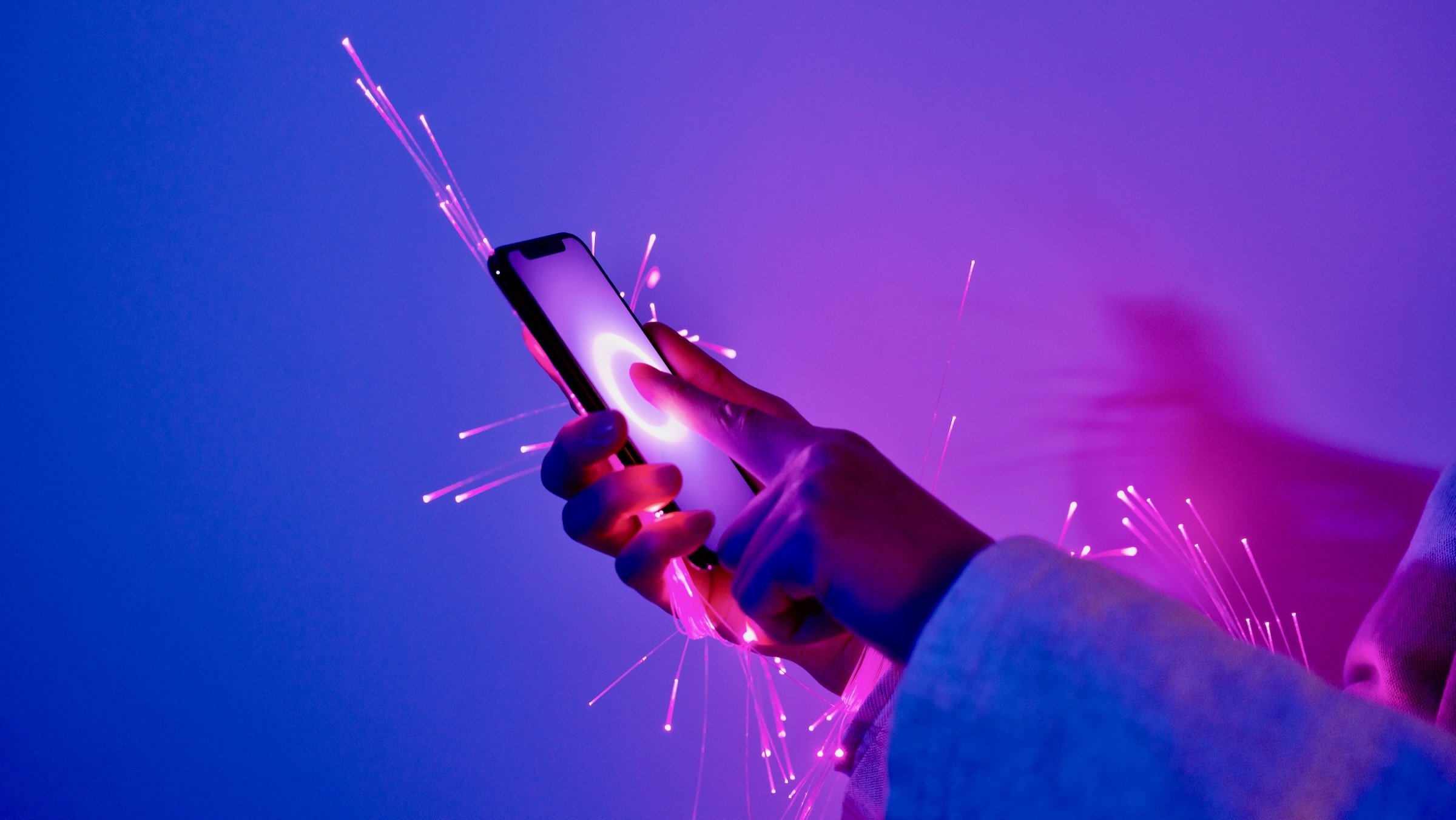 cybersecurity concept art of arm holding smartphone wrapped in glowing fiber optic cables