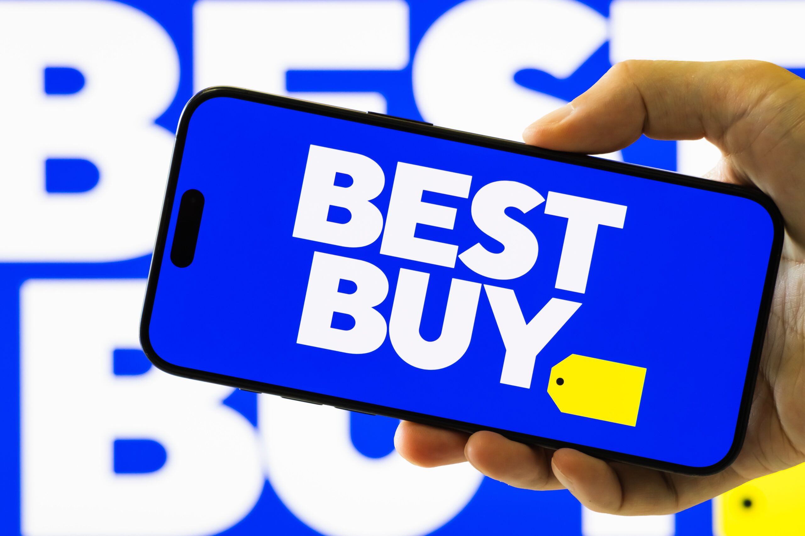 A hand holding a phone with the best buy logo.