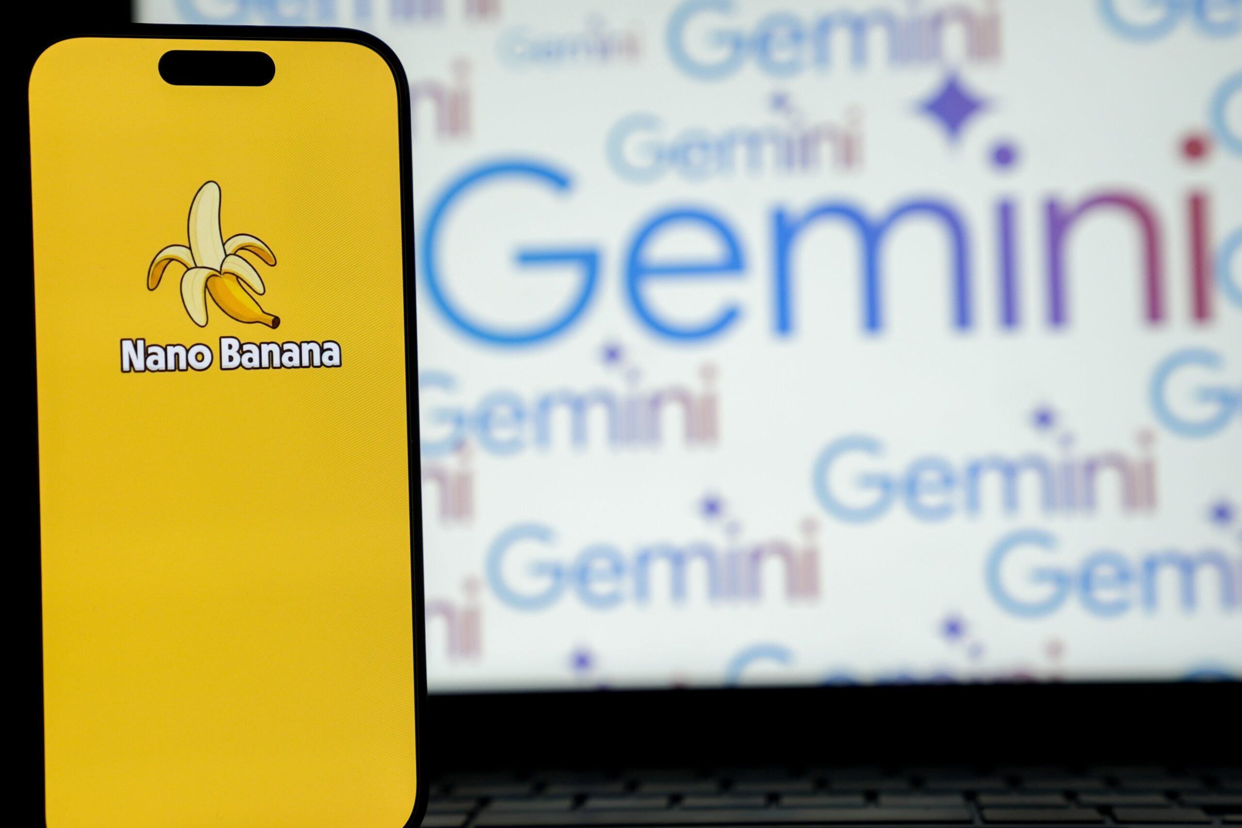 A phone shows a small banana on a yellow screen. Behind the phone is several Gemini logos.