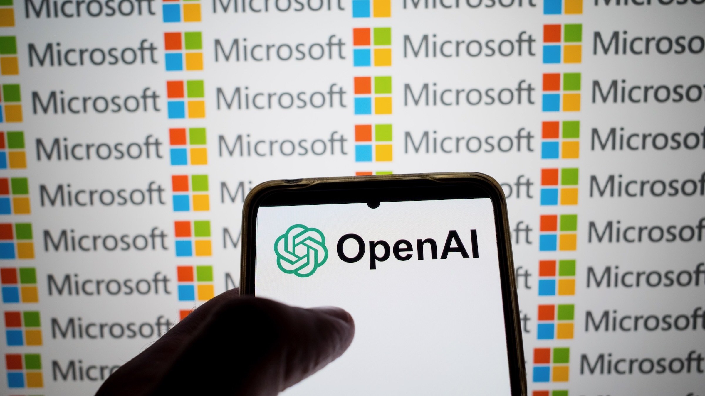  OpenAI logo appears on a smartphone screen and the Microsoft logo on a laptop screen 