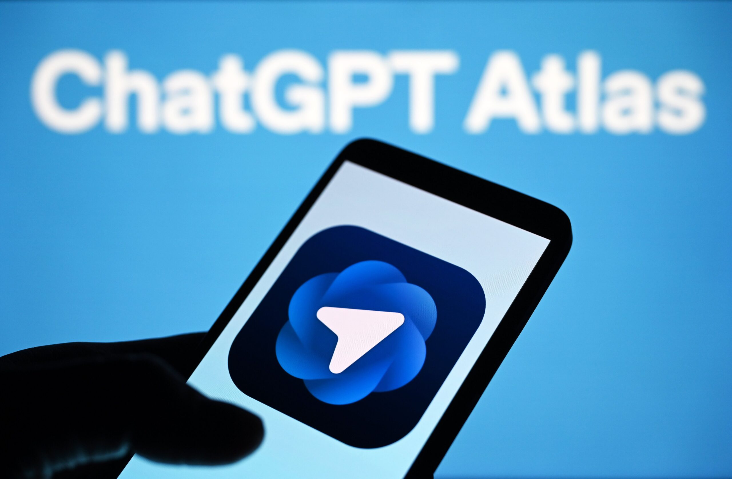 a ChatGPT Atlas logo is seen on a smartphone and in the background