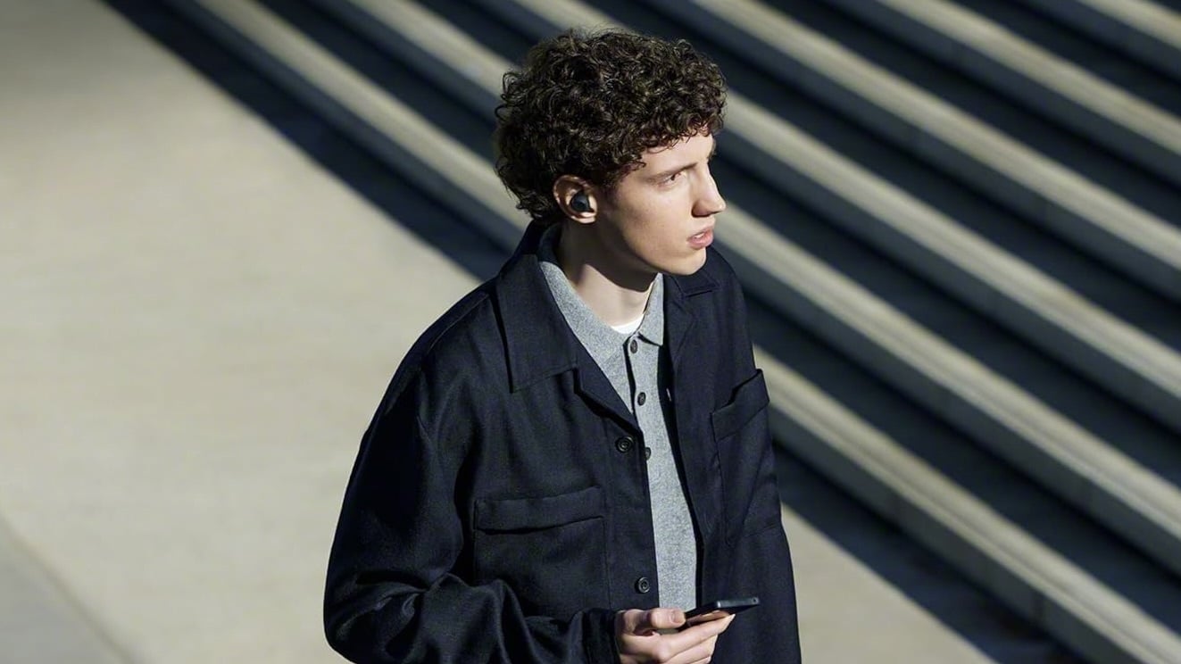 person walking outside wearing black sony wf-c710n earbuds