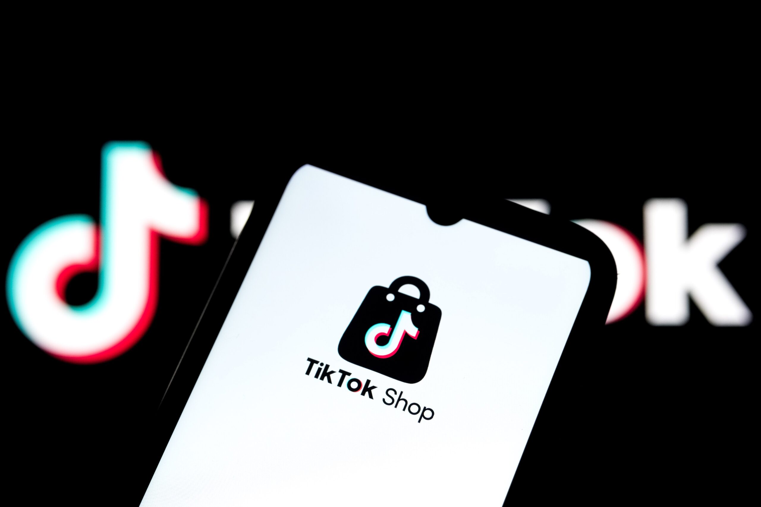 The TikTok Shop logo appears on a smartphone screen, and the TikTok logo serves as the background on a laptop computer screen in this photo illustration in Athens, Greece, on September 27, 2025.