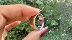 gold oura ring 4 held between fingers