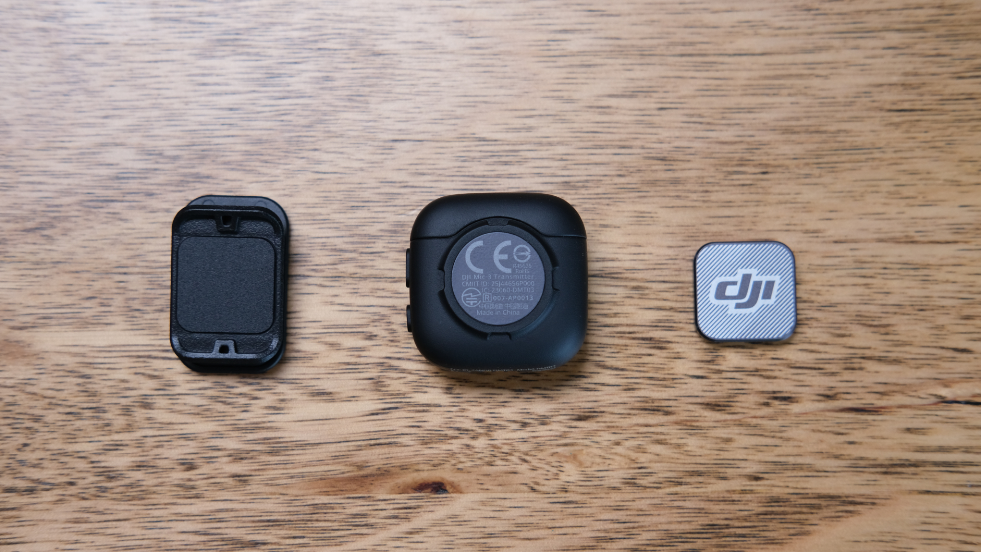 The back of the DJI Mic 3, next to a clip and magnet used to affix it to clothing.