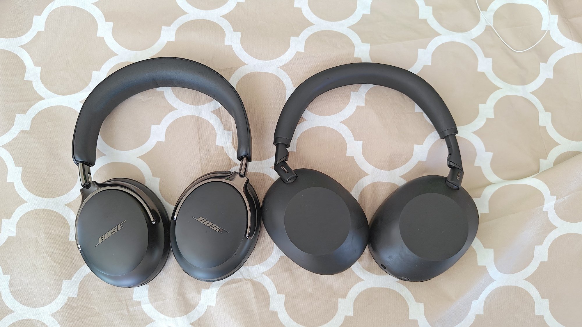 The Bose QuietComfort Ultra (Gen 2) and Sony WH-1000xM6 headphones on a patterned background