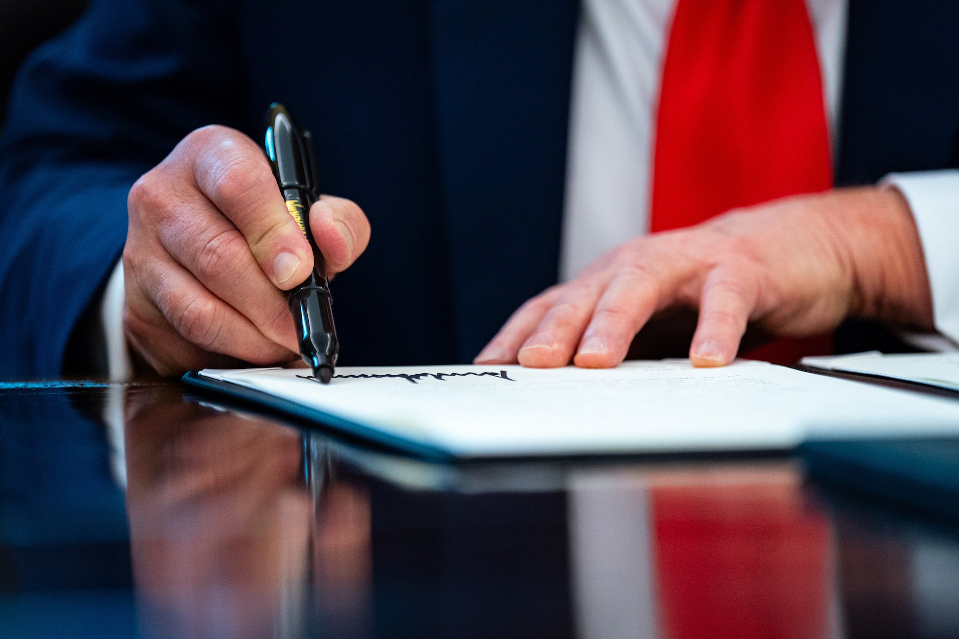 Close-up of Donald Trump's hands signing a document.