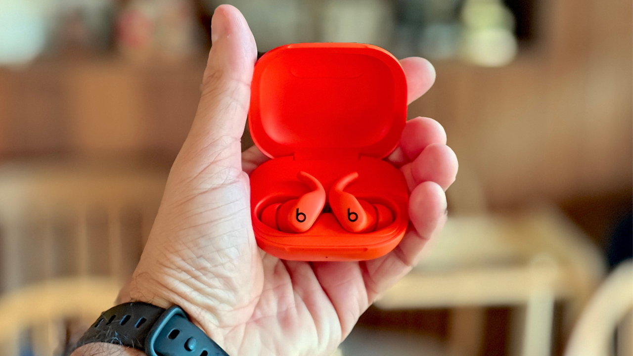 orange powerbeats fit earbuds in a man's hand