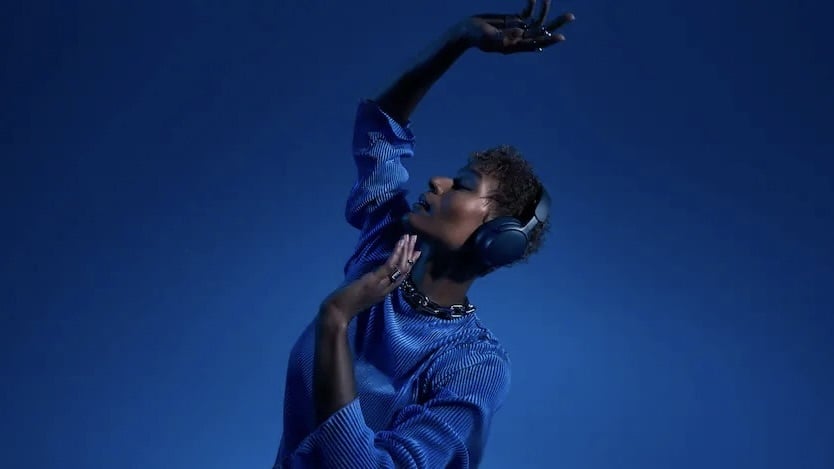 person wearing blue bose quietcomfort ultra headphones against blue background