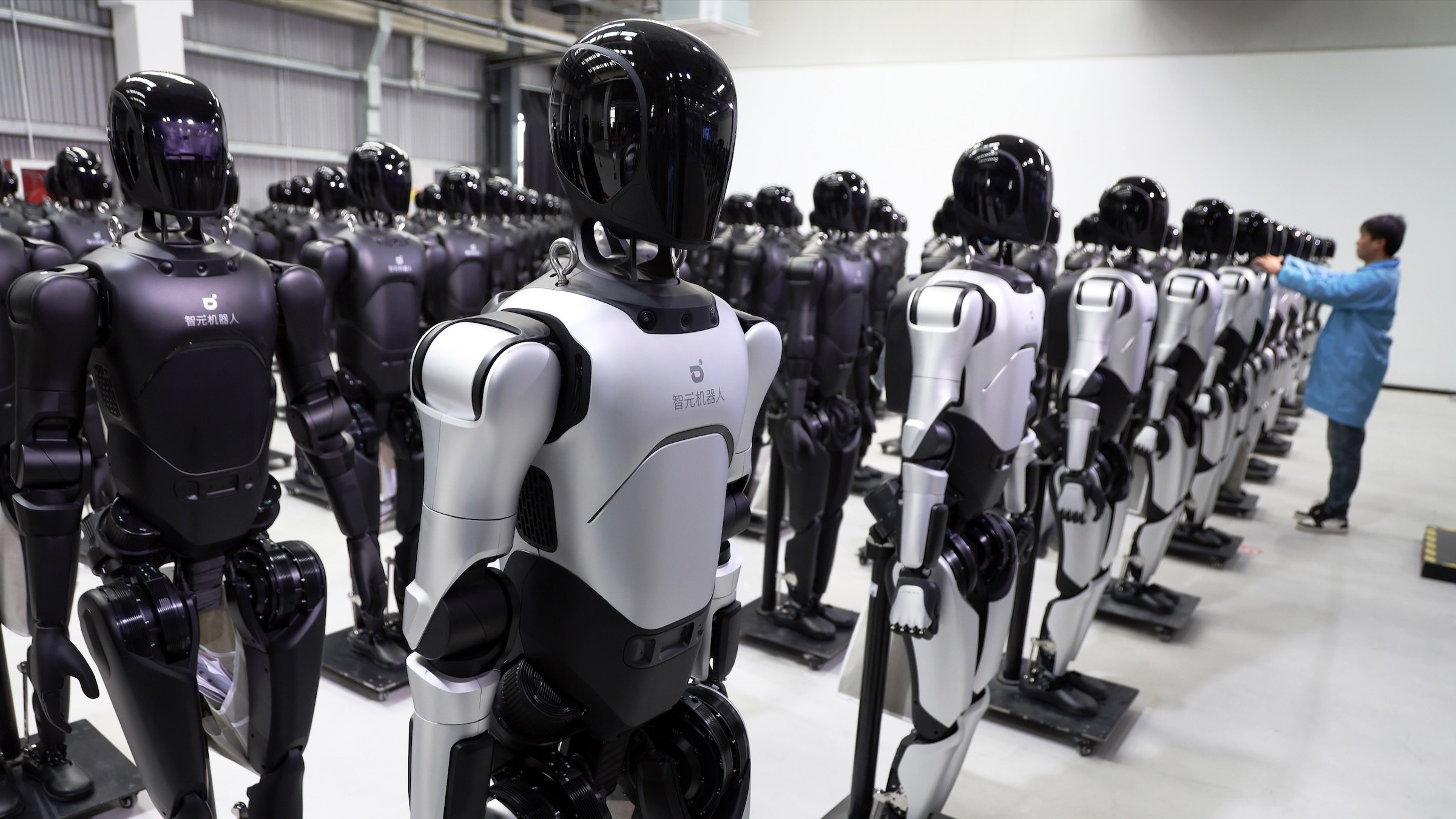 chinese engineer examining fleet of humanoid robots in AgiBot factory