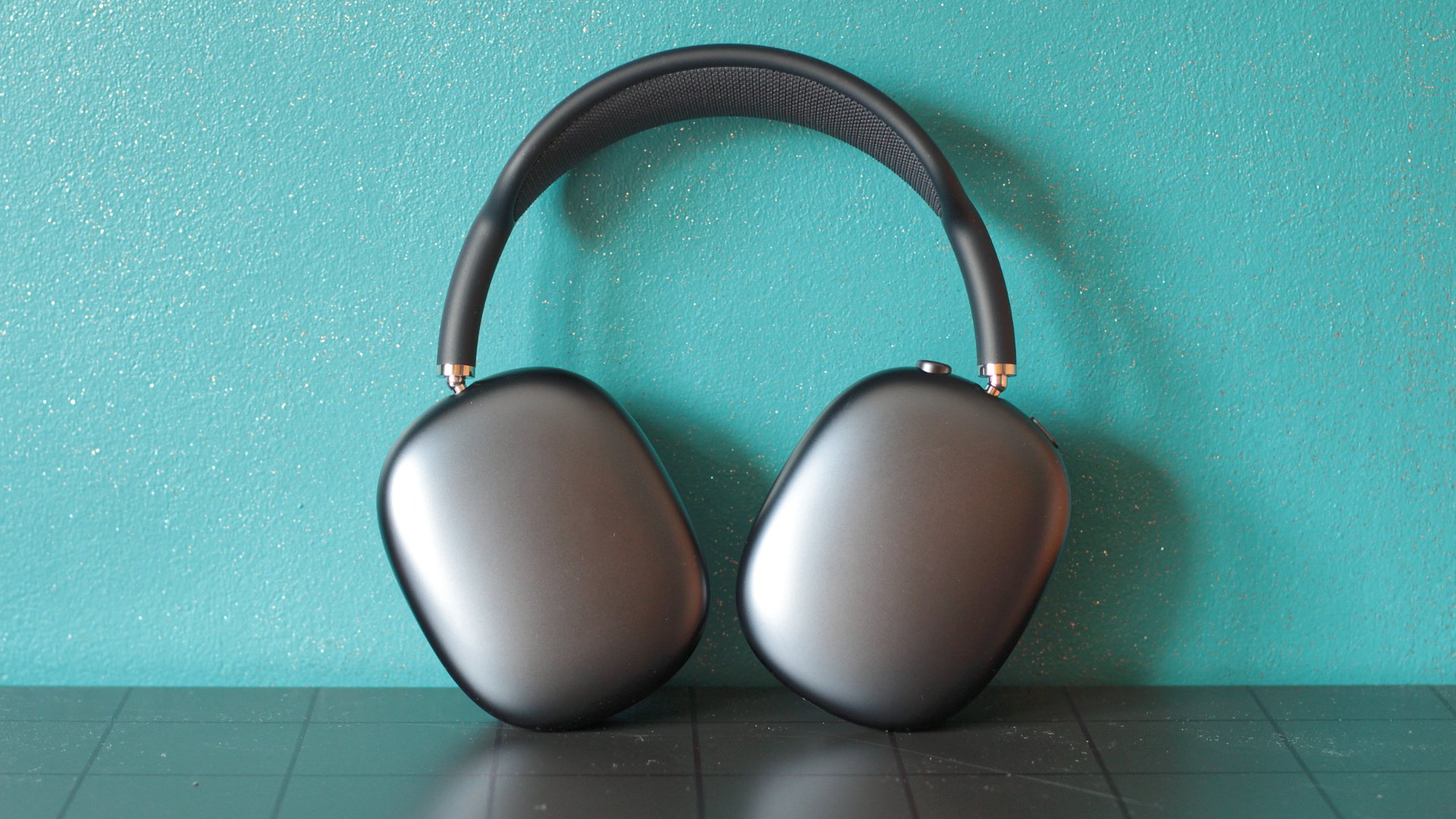 black airpods max against a teal wall