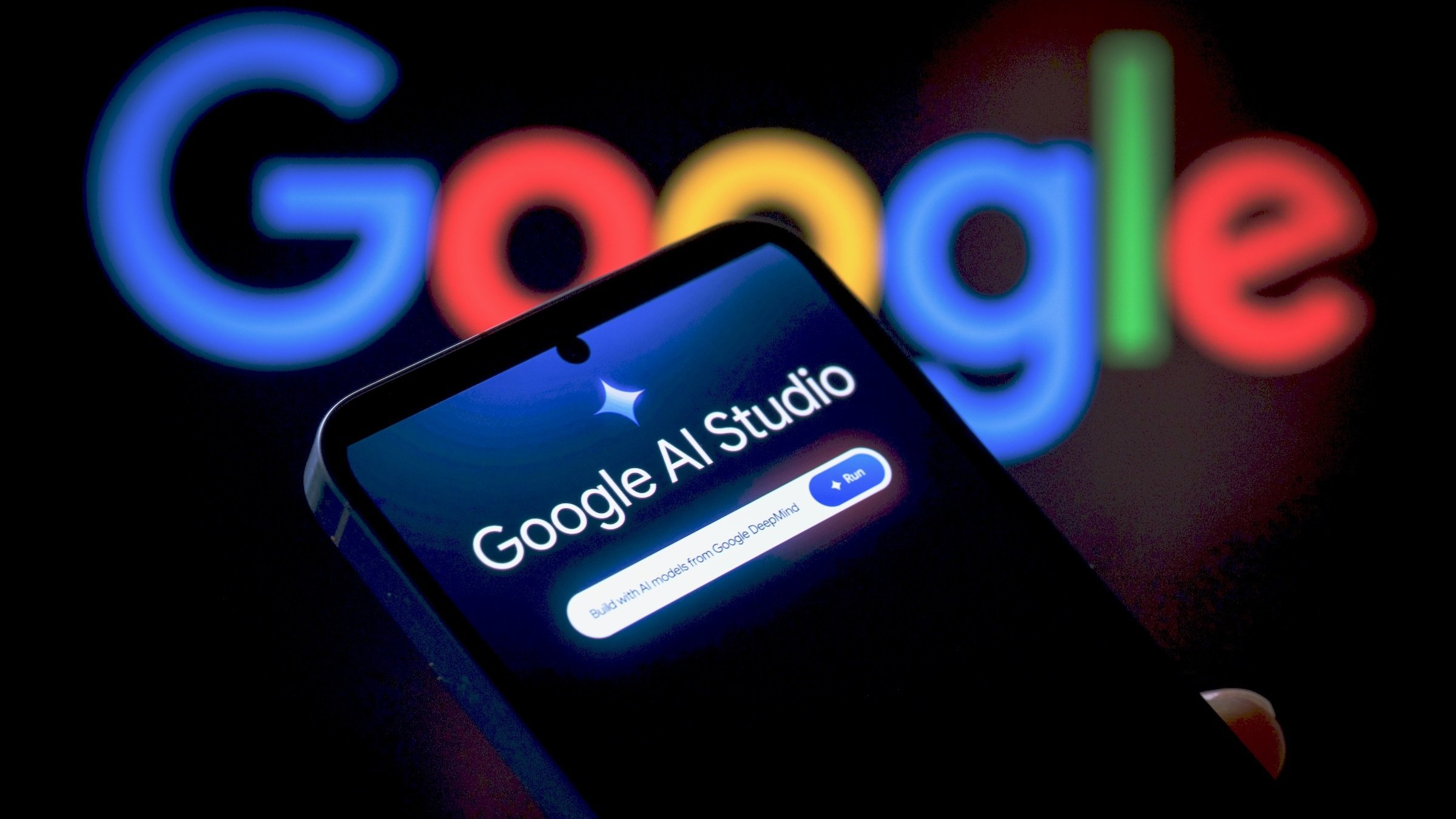 Google AI Studio application is displayed on a mobile phone with Google name in the background